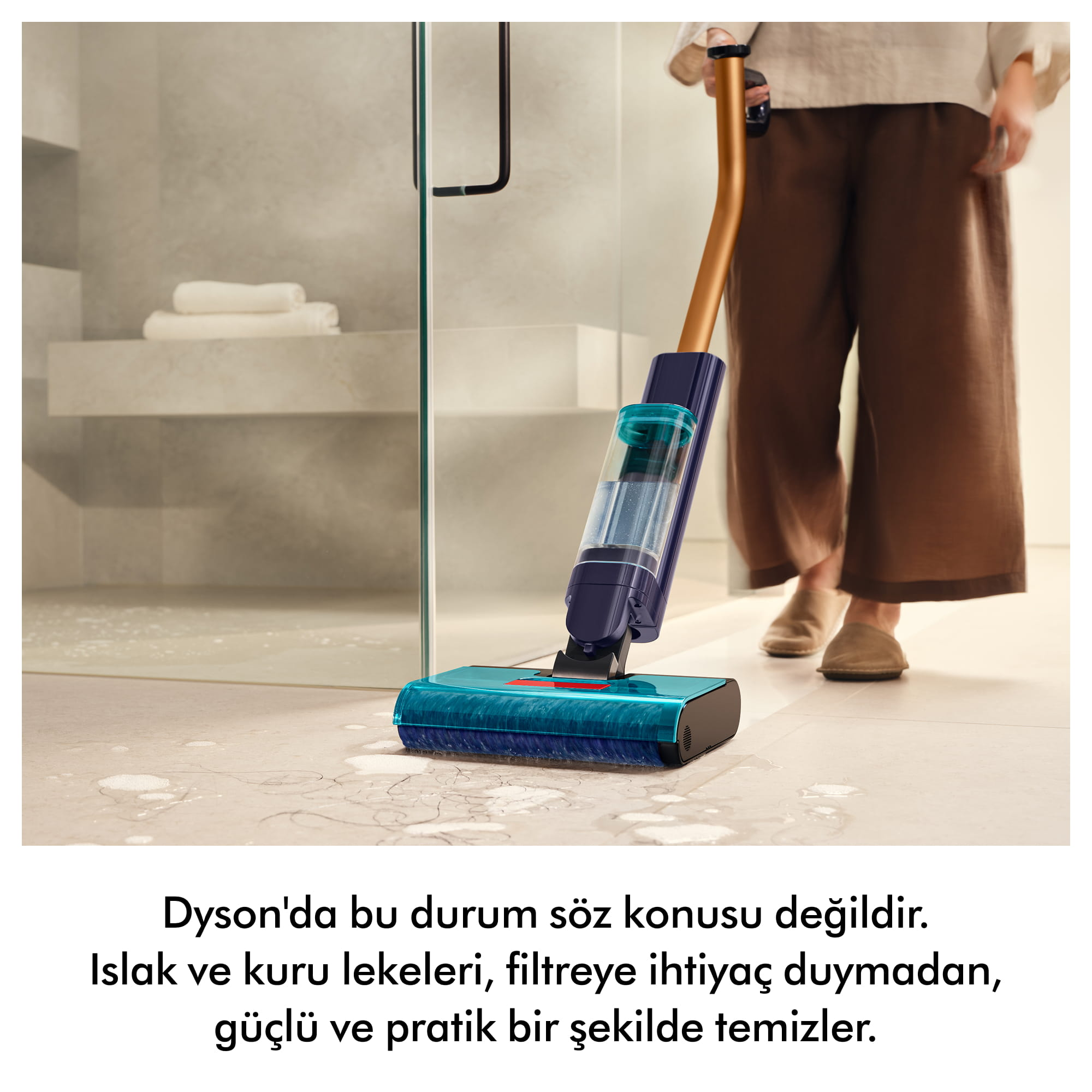 Bir kişi mavi ve altın rengi elektrikli süpürgeyle ıslak zemini temizliyor.
