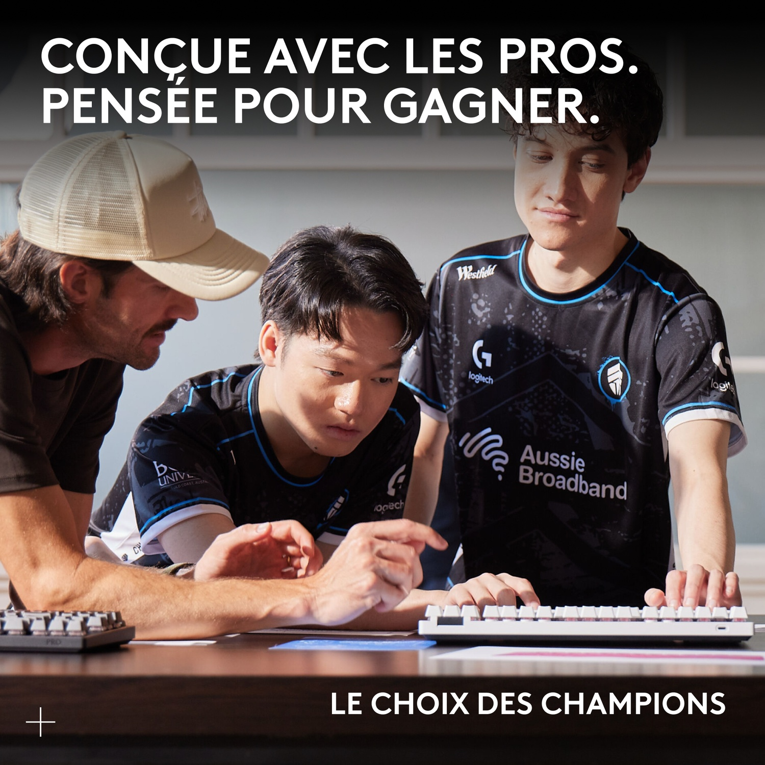 Trois hommes en maillots d'esport regardent un clavier.