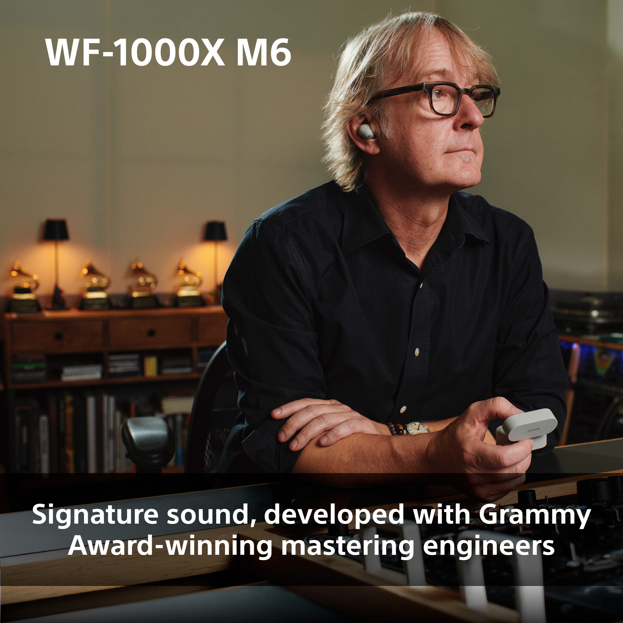 Homme avec lunettes et écouteurs dans un studio avec des prix Grammy.