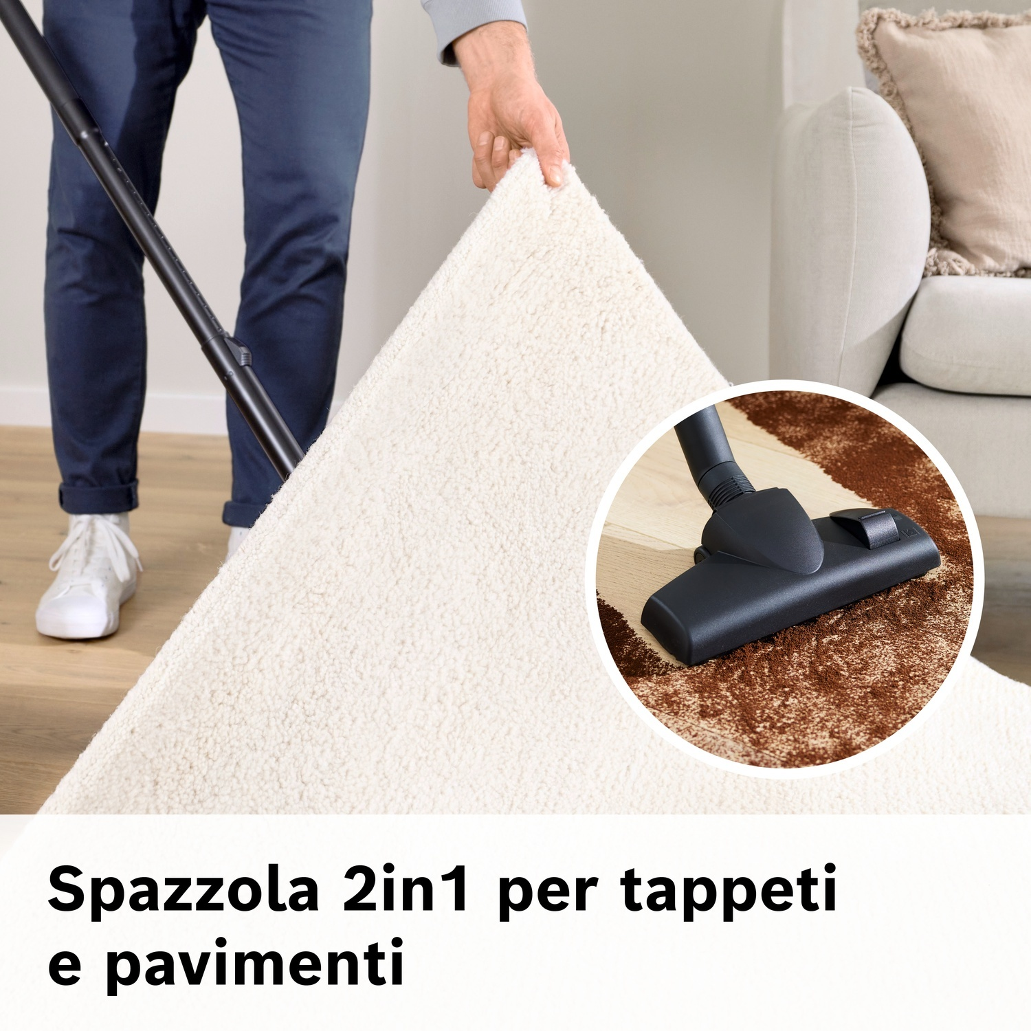 Uomo aspira tappeto bianco con aspirapolvere nero. Dettaglio mostra la spazzola.