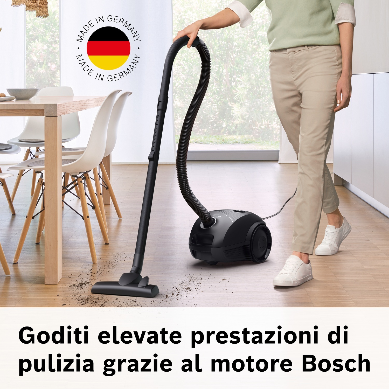 Persona aspira pavimento con aspirapolvere Bosch nero. Sigillo "Made in Germany".
