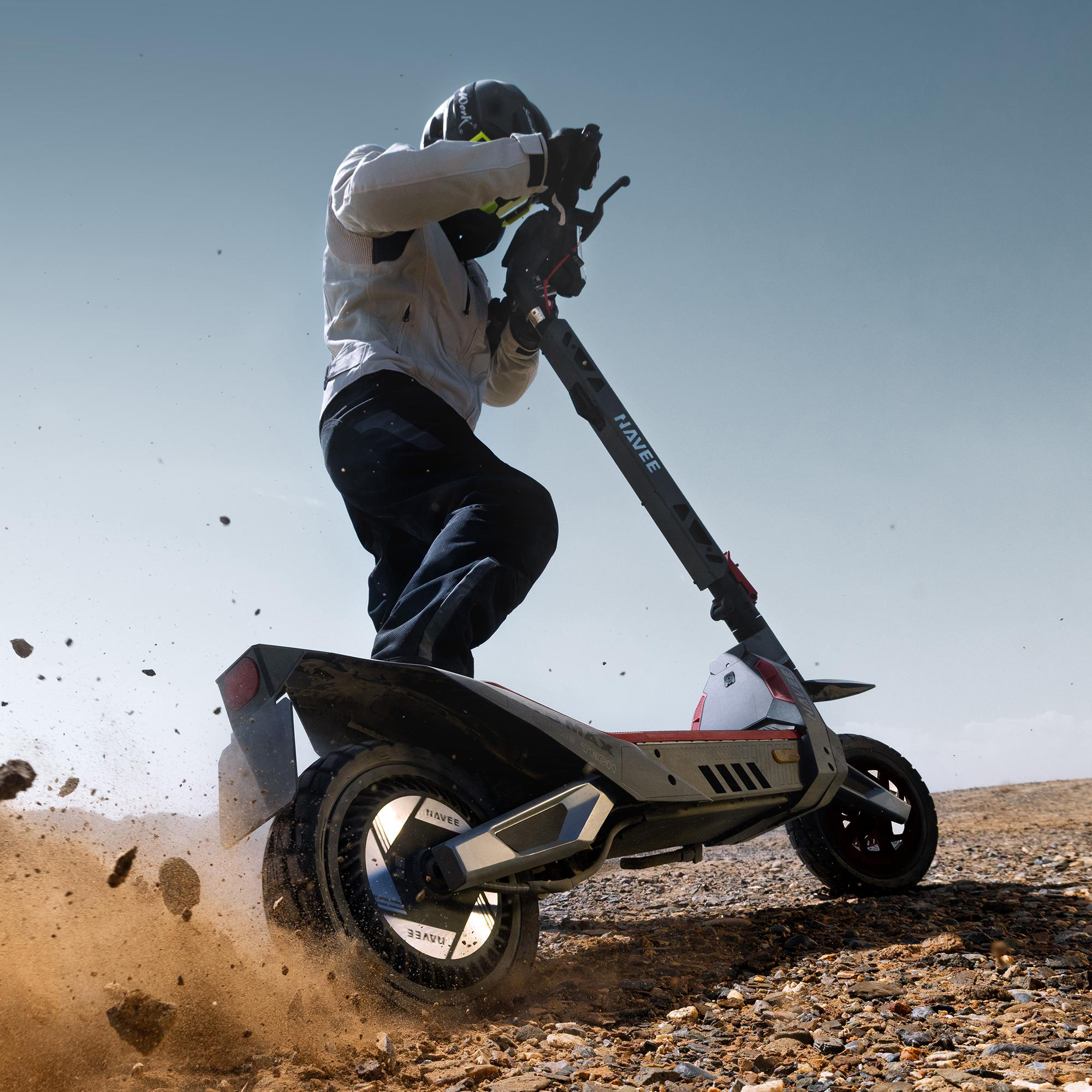 Fahrer auf E-Scooter fährt durch Schlamm und Steine im Freien.