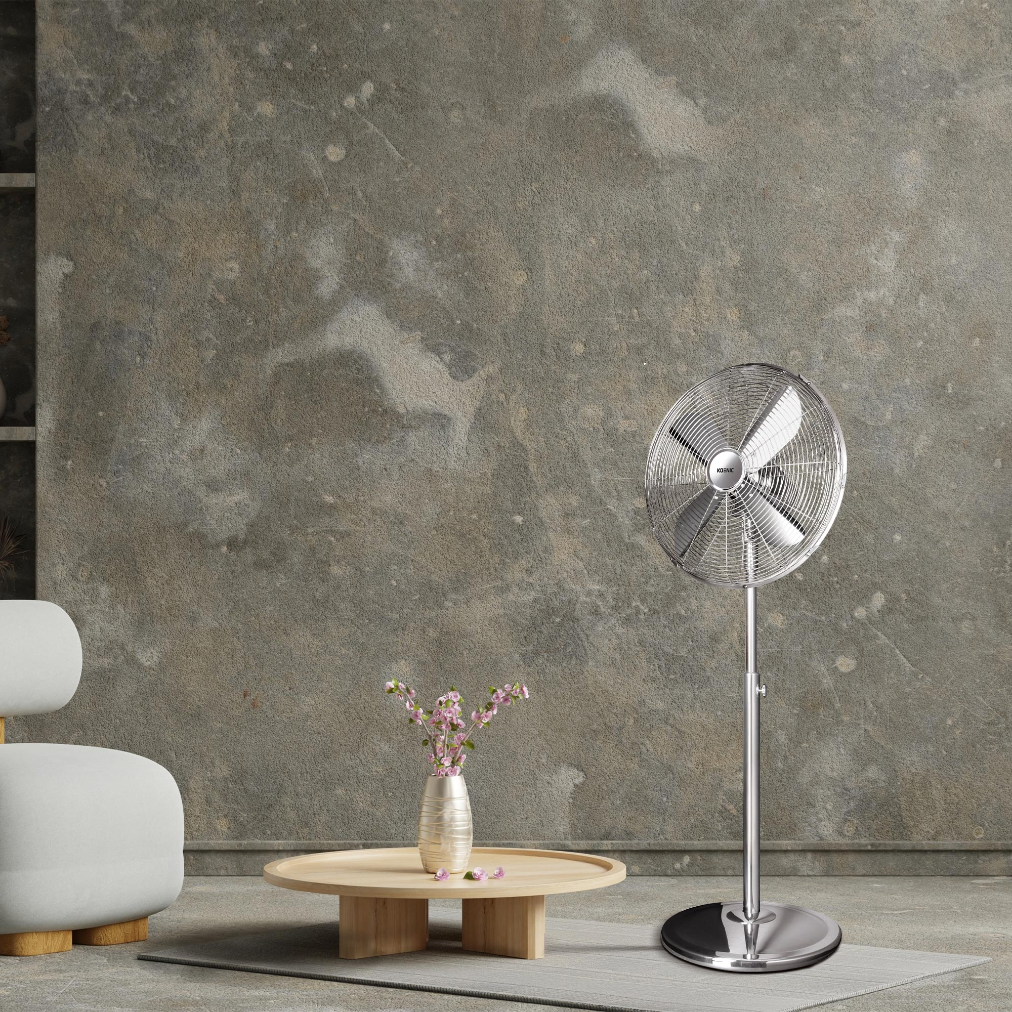 Srebrny wentylator stojący obok okrągłego drewnianego stołu z wazonem kwiatów.
