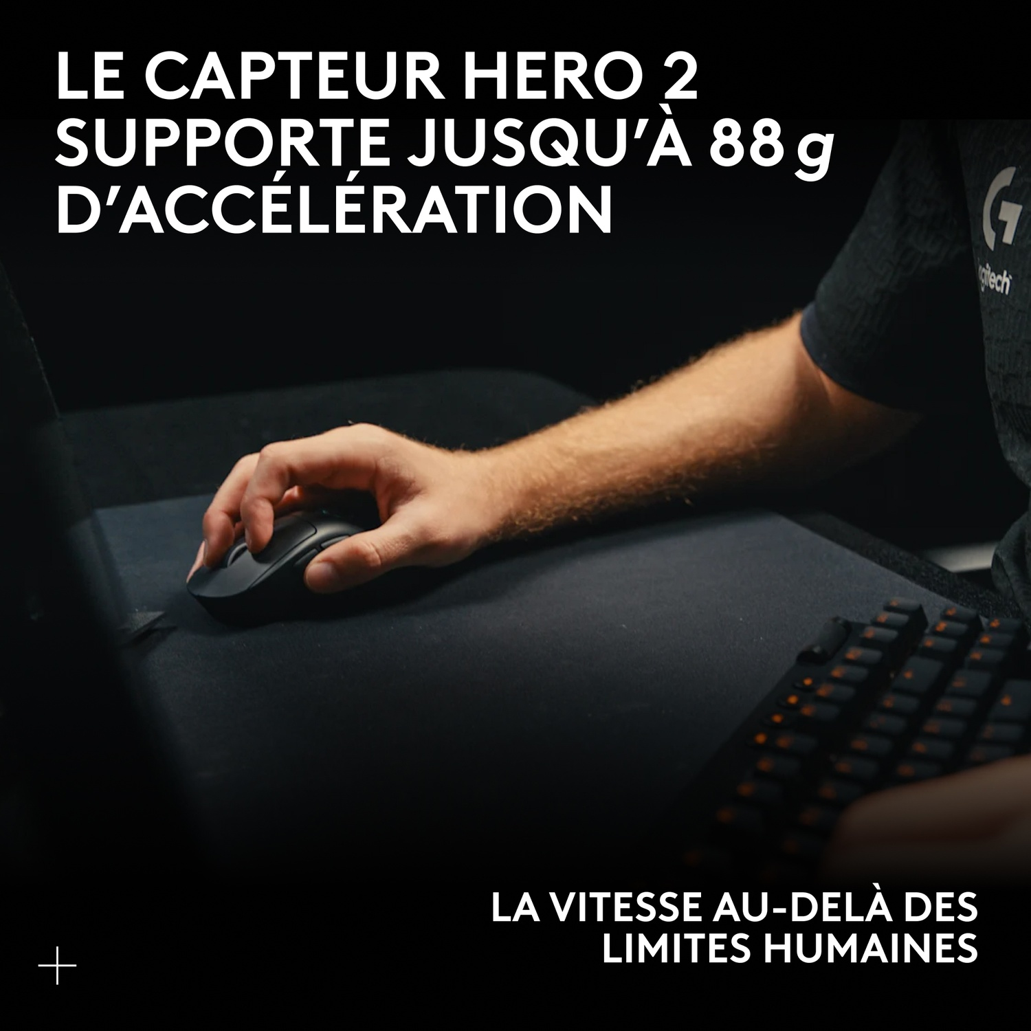 Une main utilise une souris Logitech noire à côté d'un clavier rétroéclairé en orange.