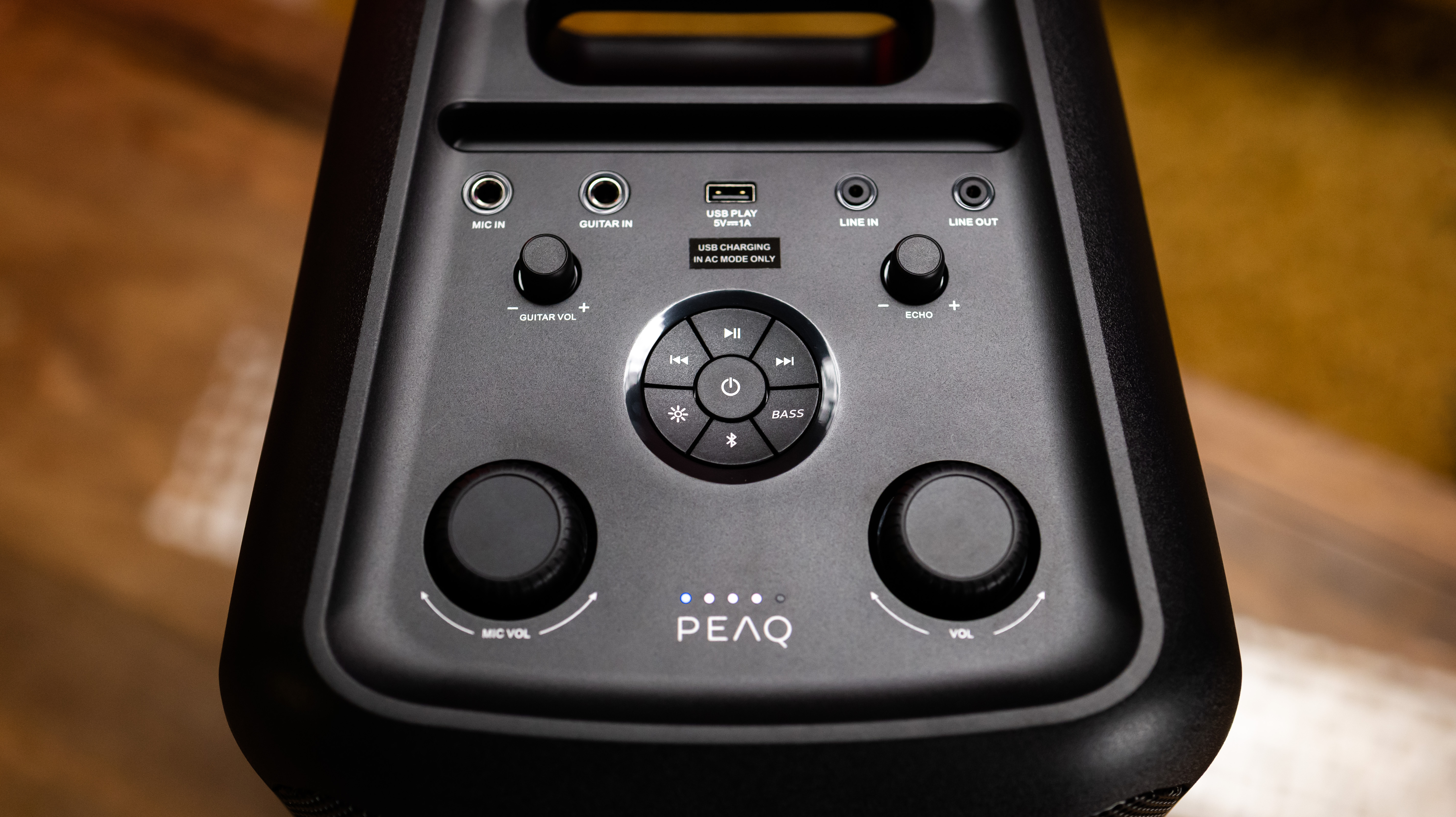 Zbliżenie na elementy sterujące czarnego głośnika PEAQ z gałkami i przyciskami.