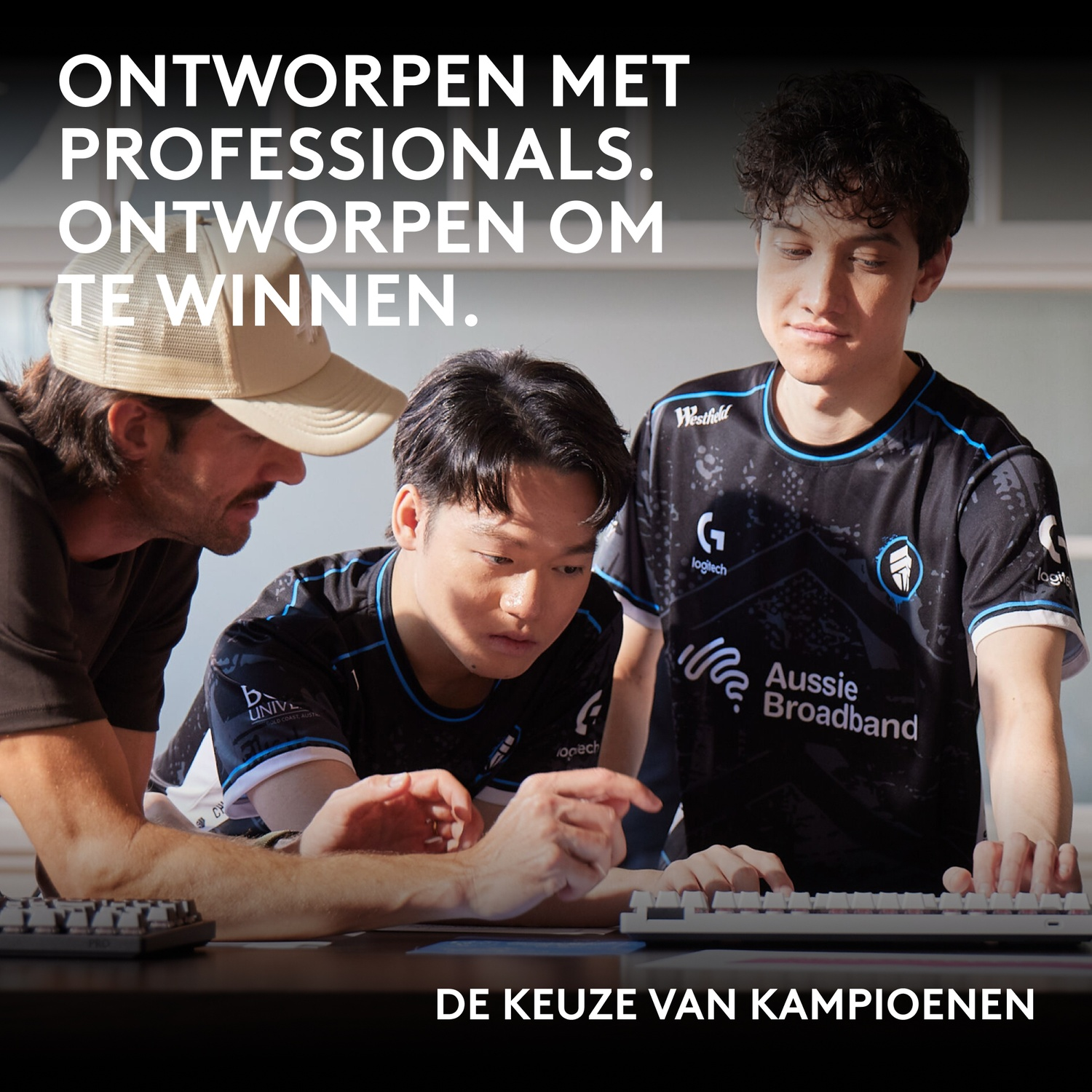 Three esports players in black jerseys look down at a table. Text above and below.