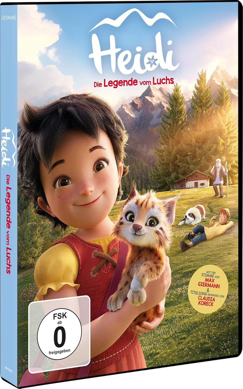 Heidi hält eine Katze, Berge und Wald im Hintergrund.