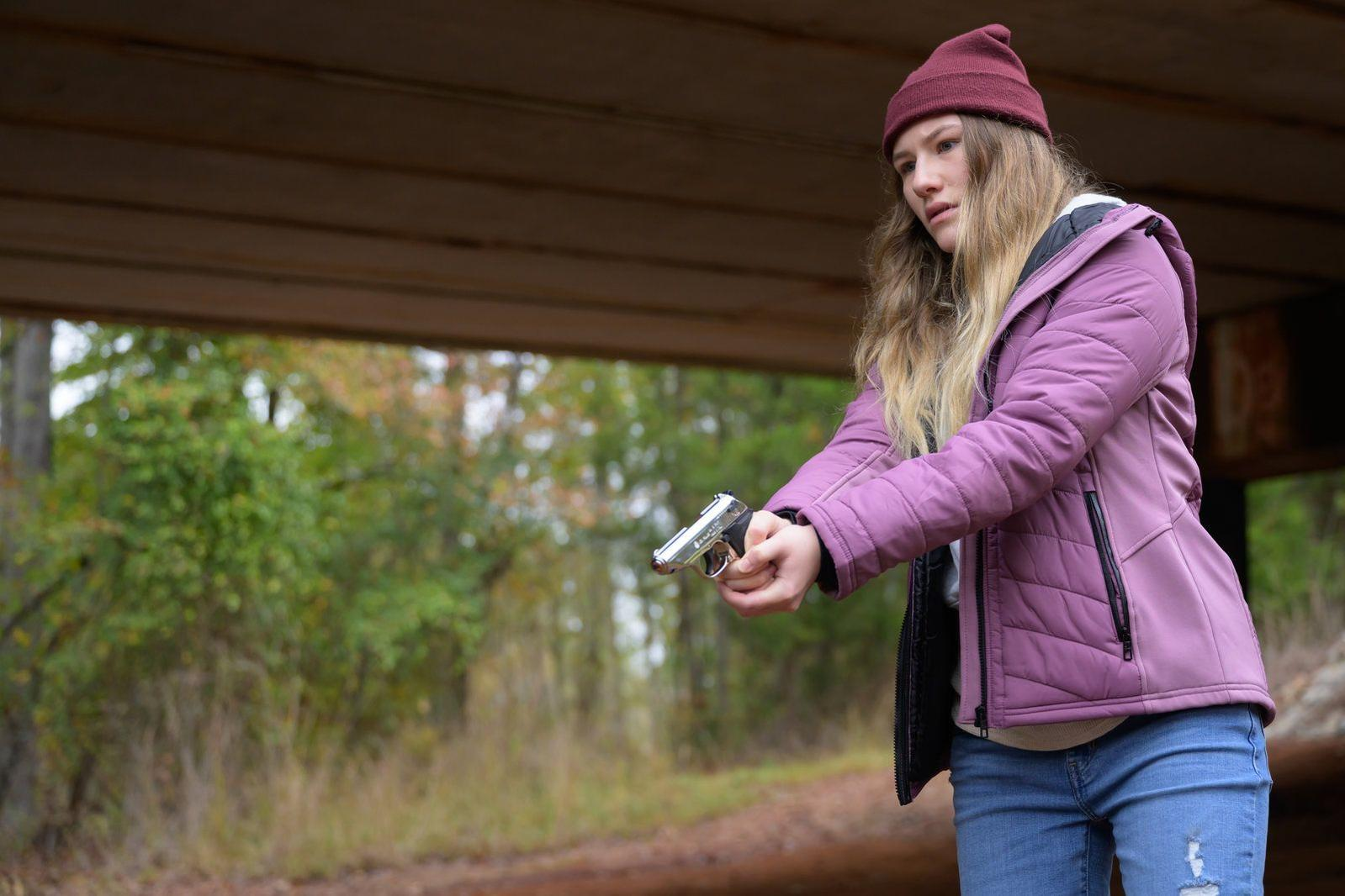 Mädchen mit Waffe unter einer Brücke, im Wald