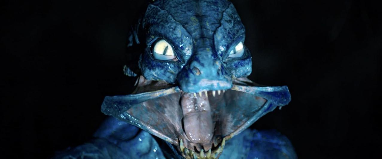 Ein blaues Monster mit gelben Augen und weit geöffnetem Maul.