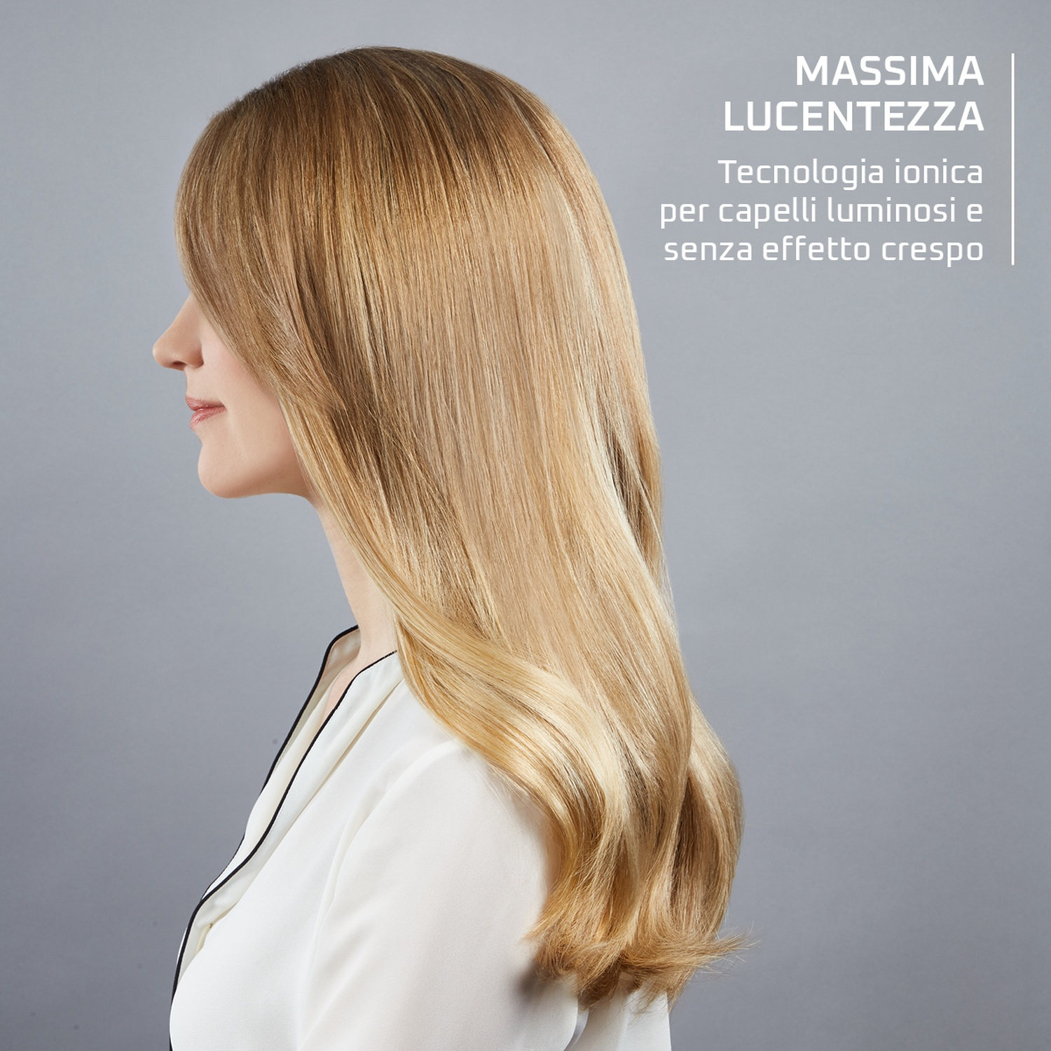 Donna con capelli biondi luminosi, vista di profilo, sfondo grigio.