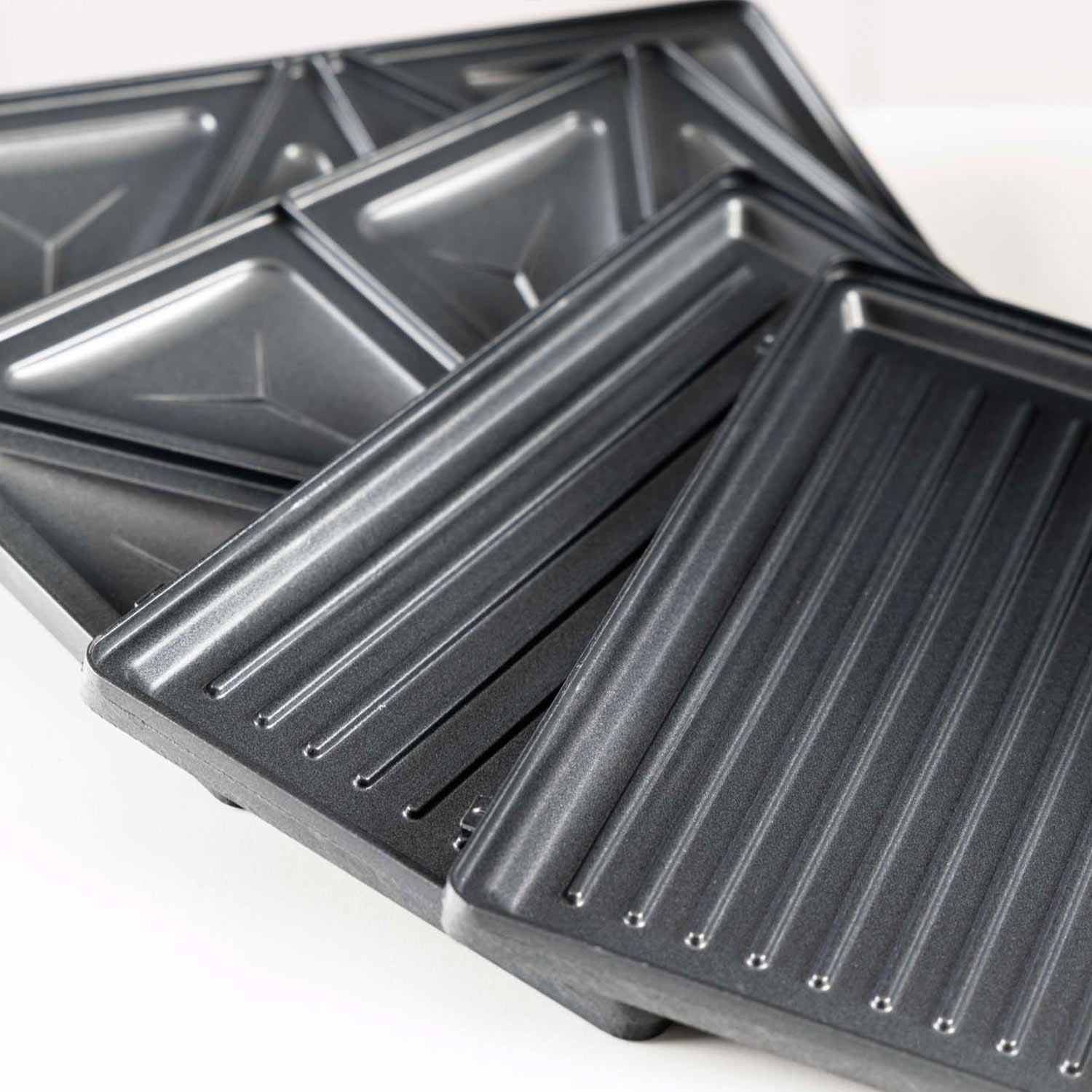 Varias placas antiadherentes para sándwiches con formas acanaladas y triangulares.
