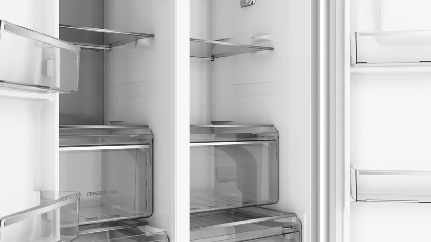 Vista interior de un refrigerador moderno y vacío con estantes y cajones de cristal.