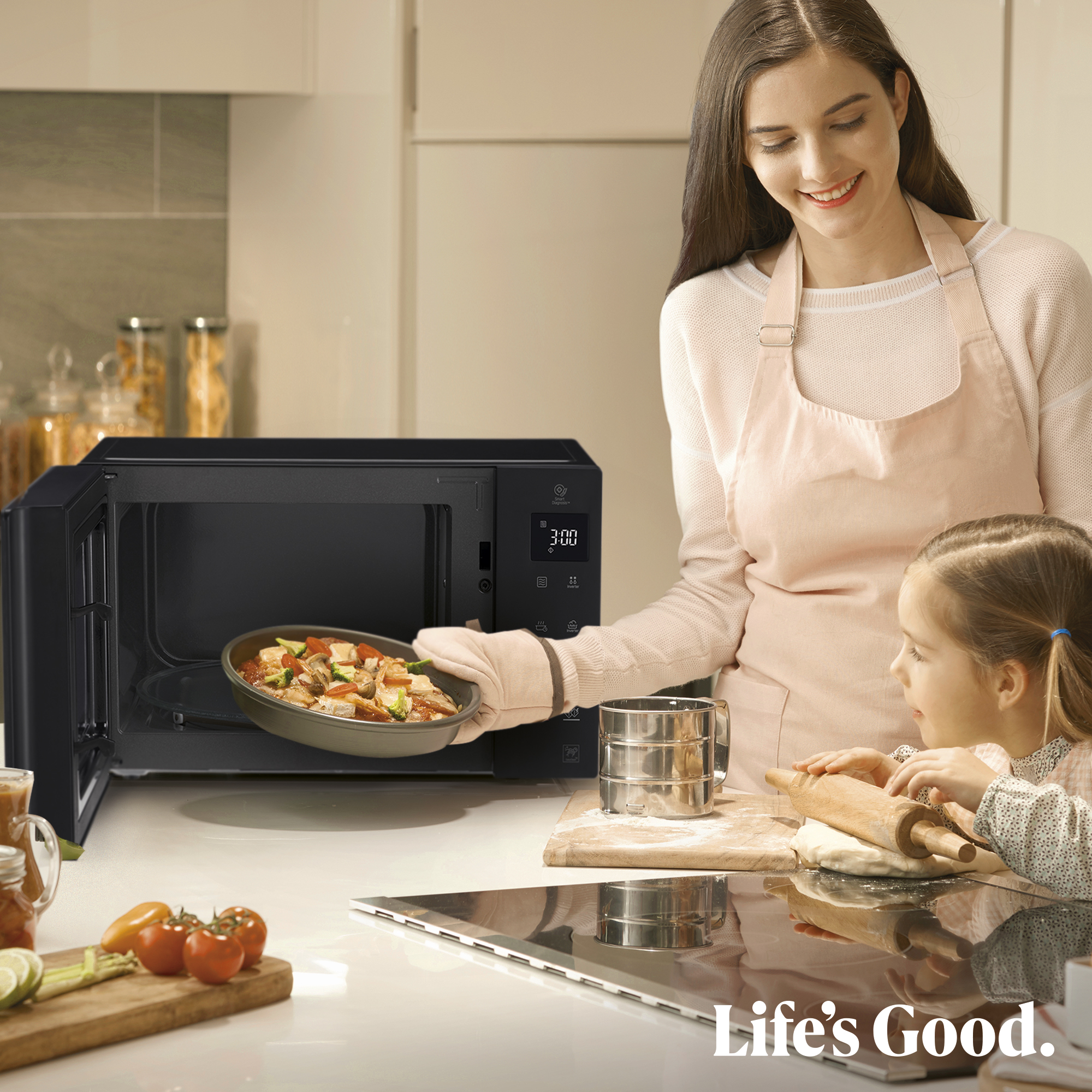 Madre e hija en cocina, sacando comida del microondas.