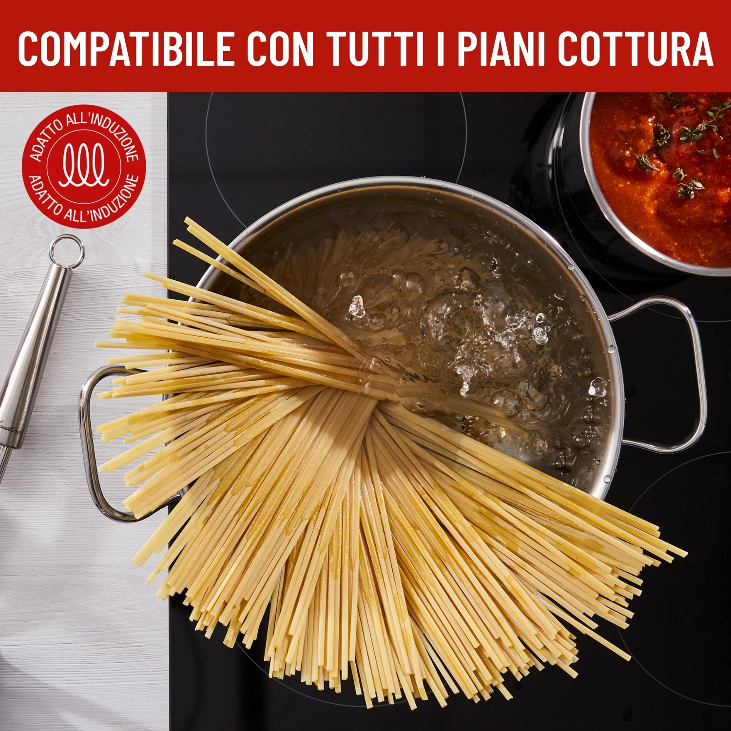 Spaghetti cotti in pentola su piano cottura a induzione, accanto a una pentola di salsa di pomodoro.