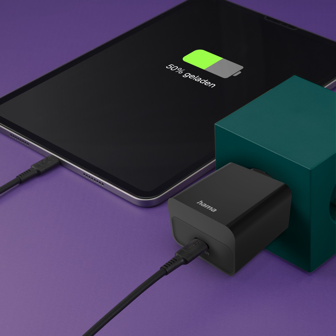 Egy táblagép USB-kábellel csatlakozik egy fekete Hama töltőhöz.