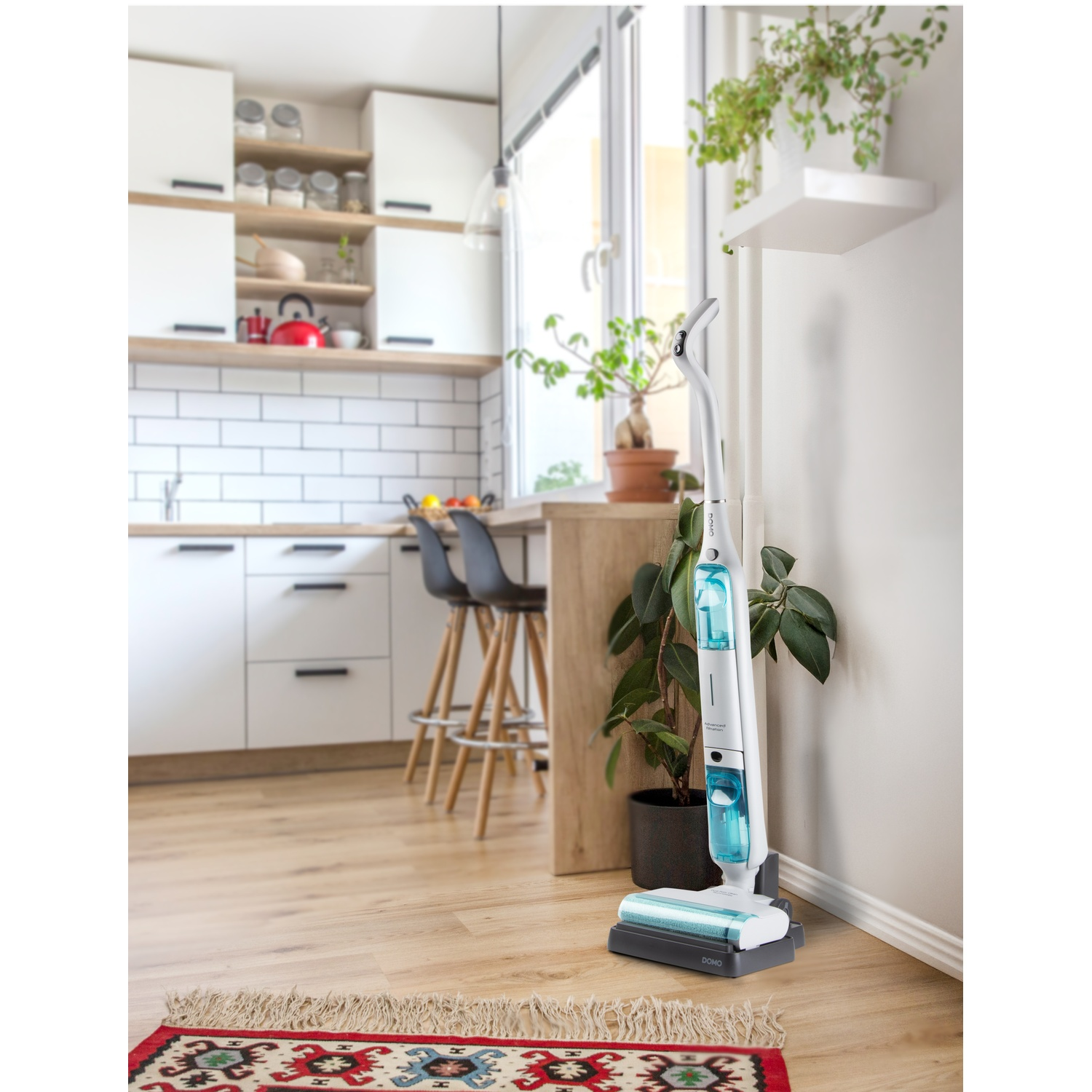 Un balai serpillière sans fil se trouve dans une cuisine moderne près d'une plante.