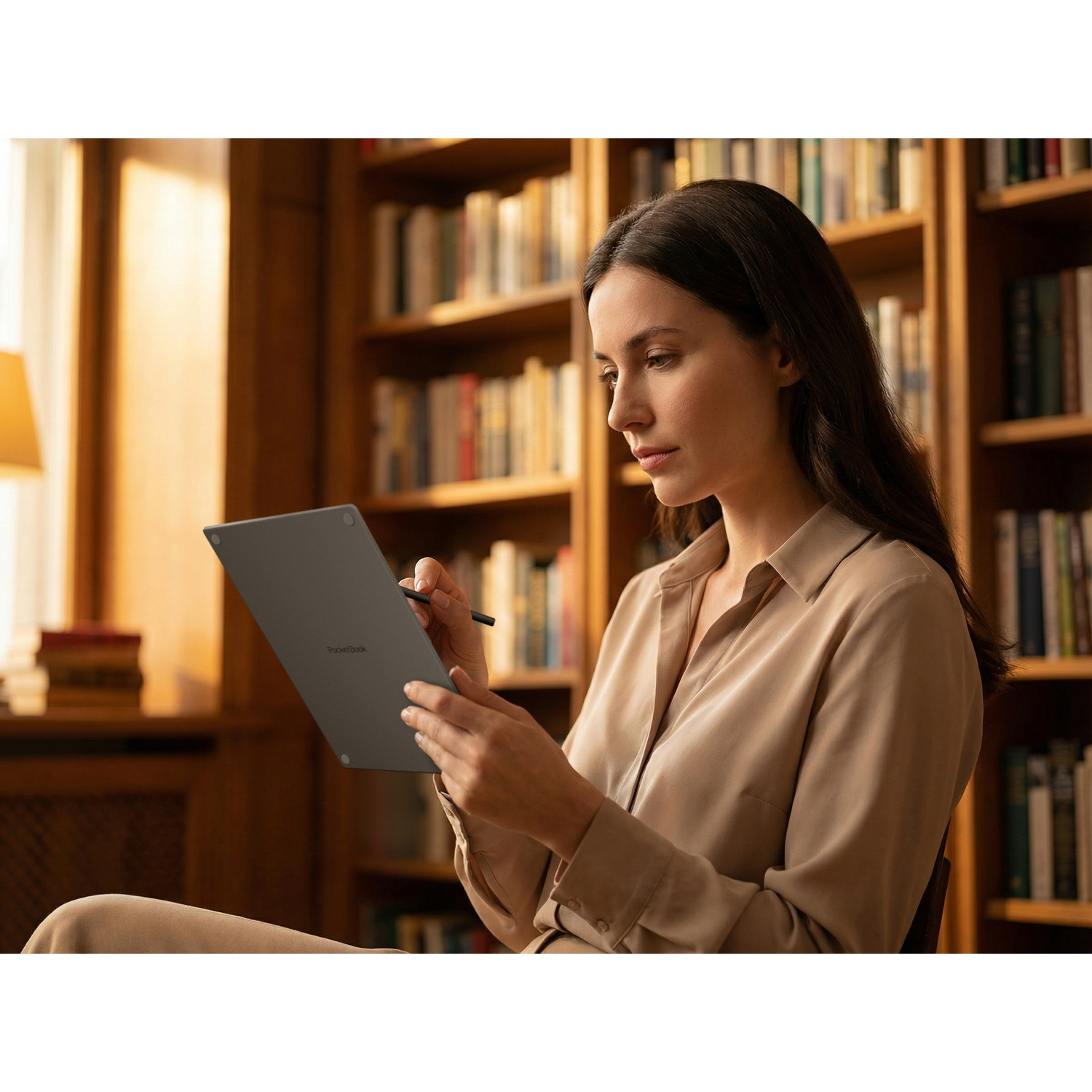Femme en chemise beige utilise une tablette dans une bibliothèque.