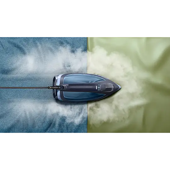 Żelazko parowe na niebieskiej i zielonej tkaninie z parą.