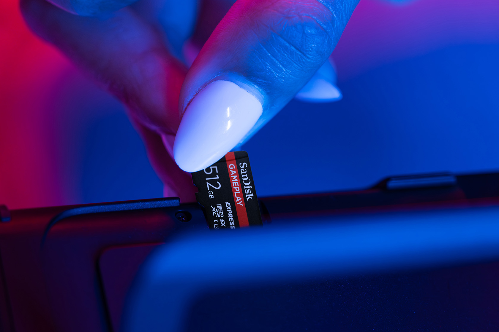 Une main insère une carte mémoire SanDisk de 512 Go dans un appareil.