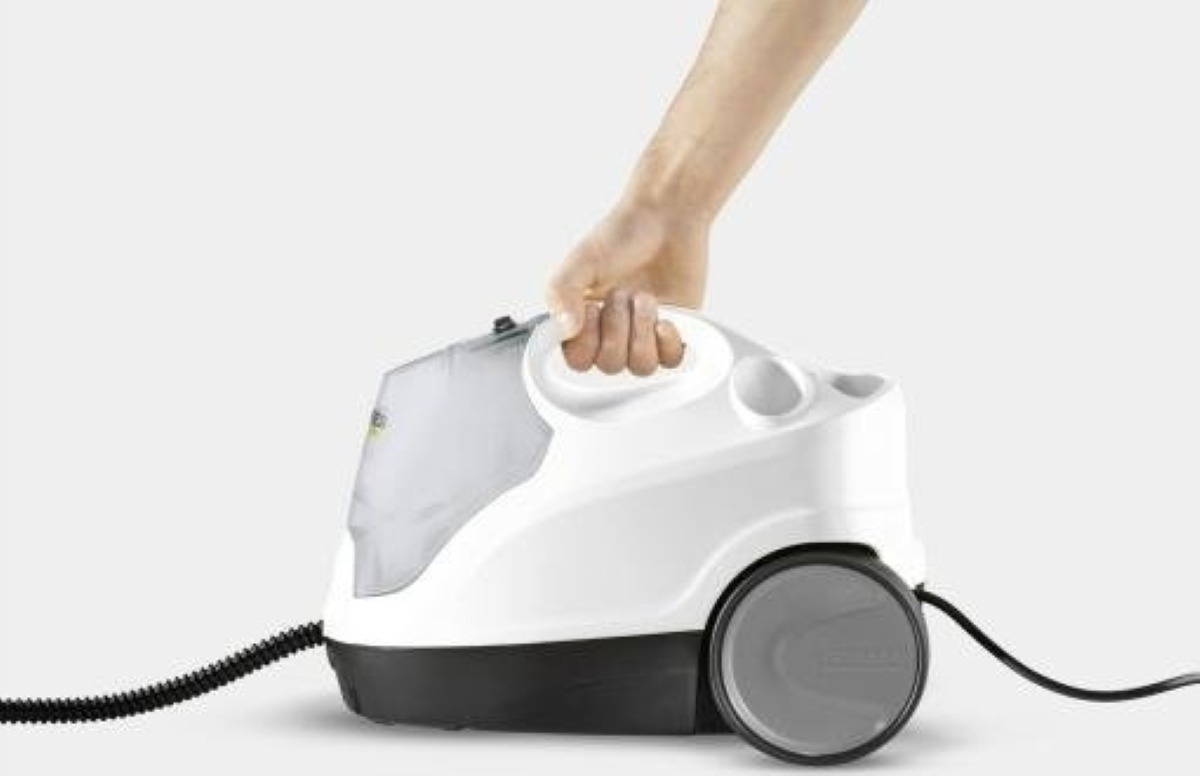 Biała parownica z czarnym wężem, trzymana przez rękę.