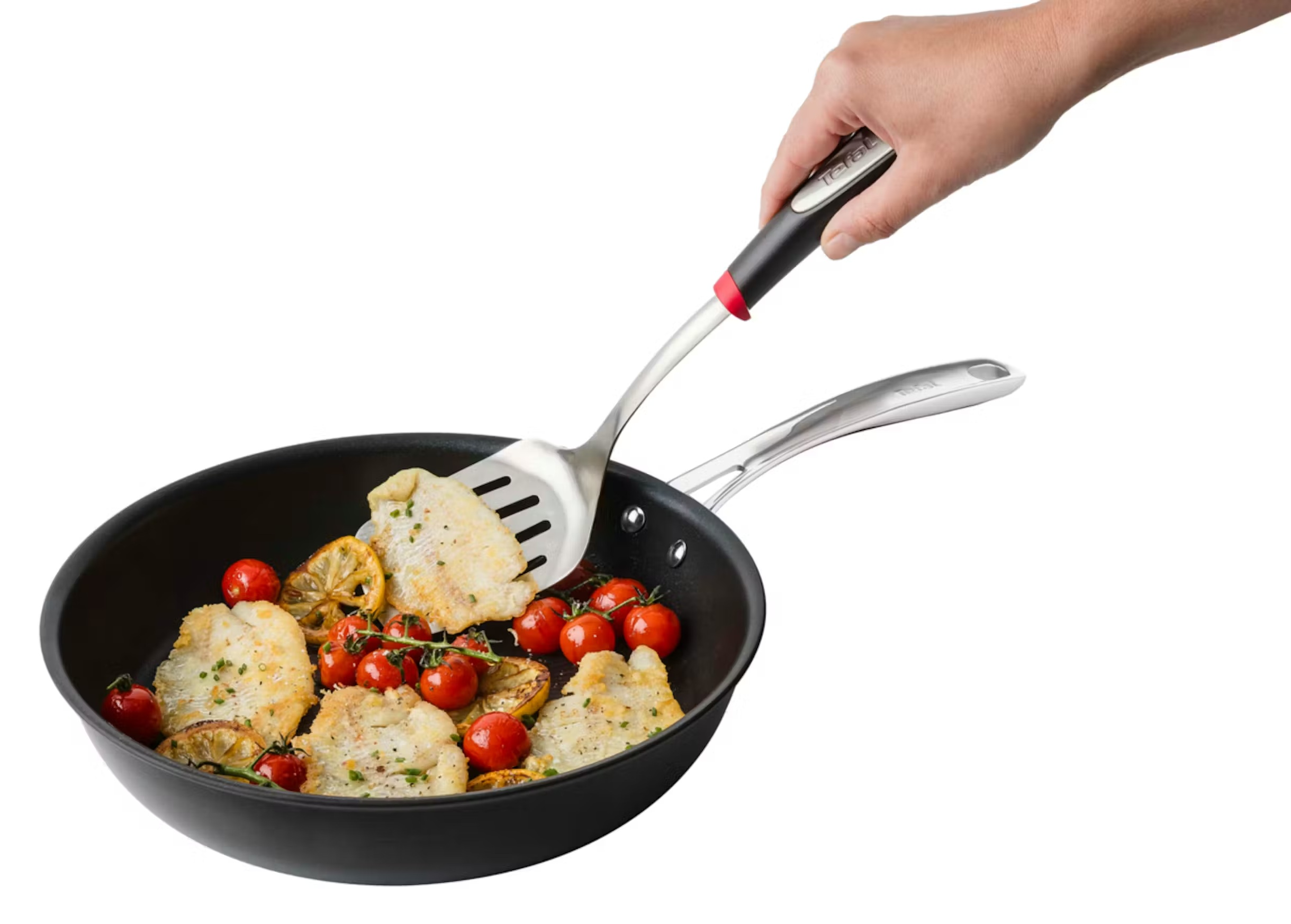 Ryba z pomidorami i cytryną na patelni, obracana łopatką.