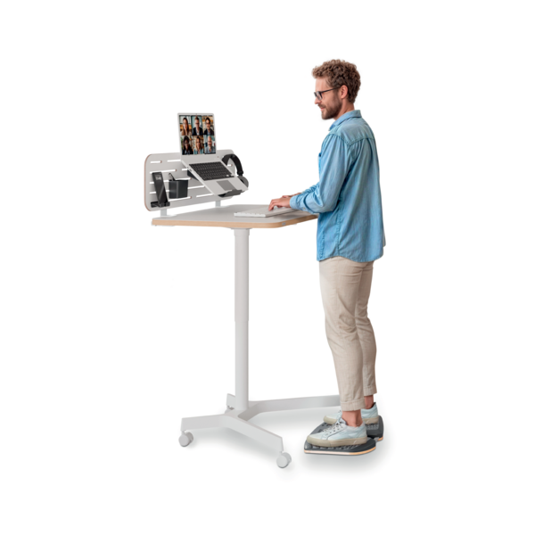 Mann am Stehschreibtisch tippt auf Tastatur, Laptop zeigt Videokonferenz.