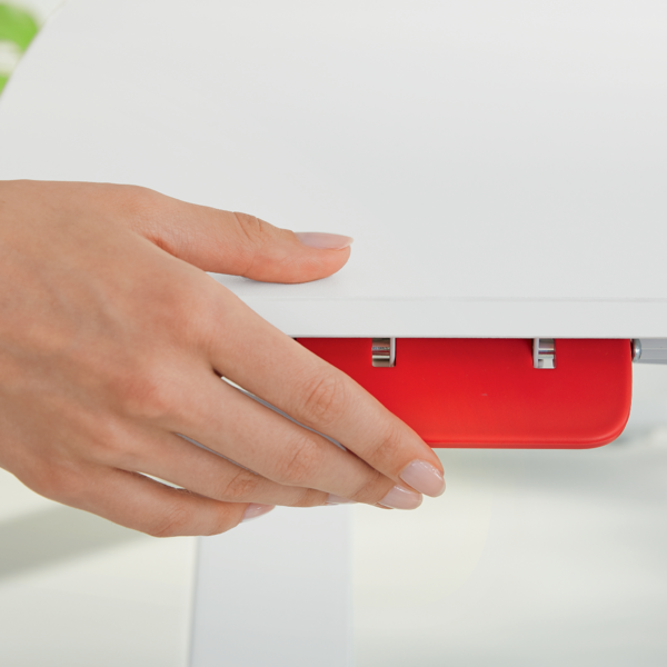 Eine Hand mit Nagellack berührt eine rote Schublade unter einem weißen Tisch.