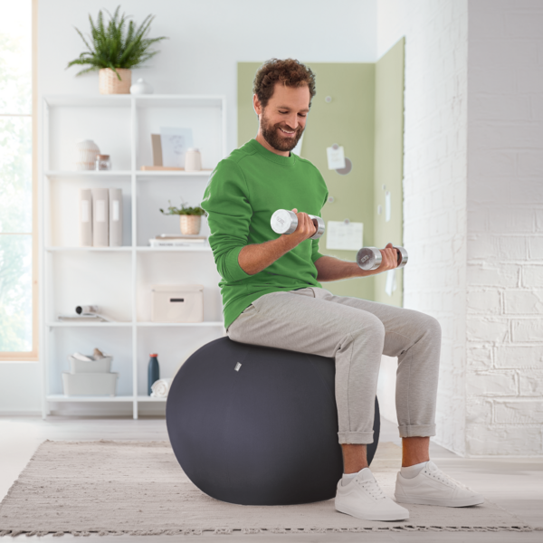 Ein Mann trainiert mit Hanteln auf einem Gymnastikball.