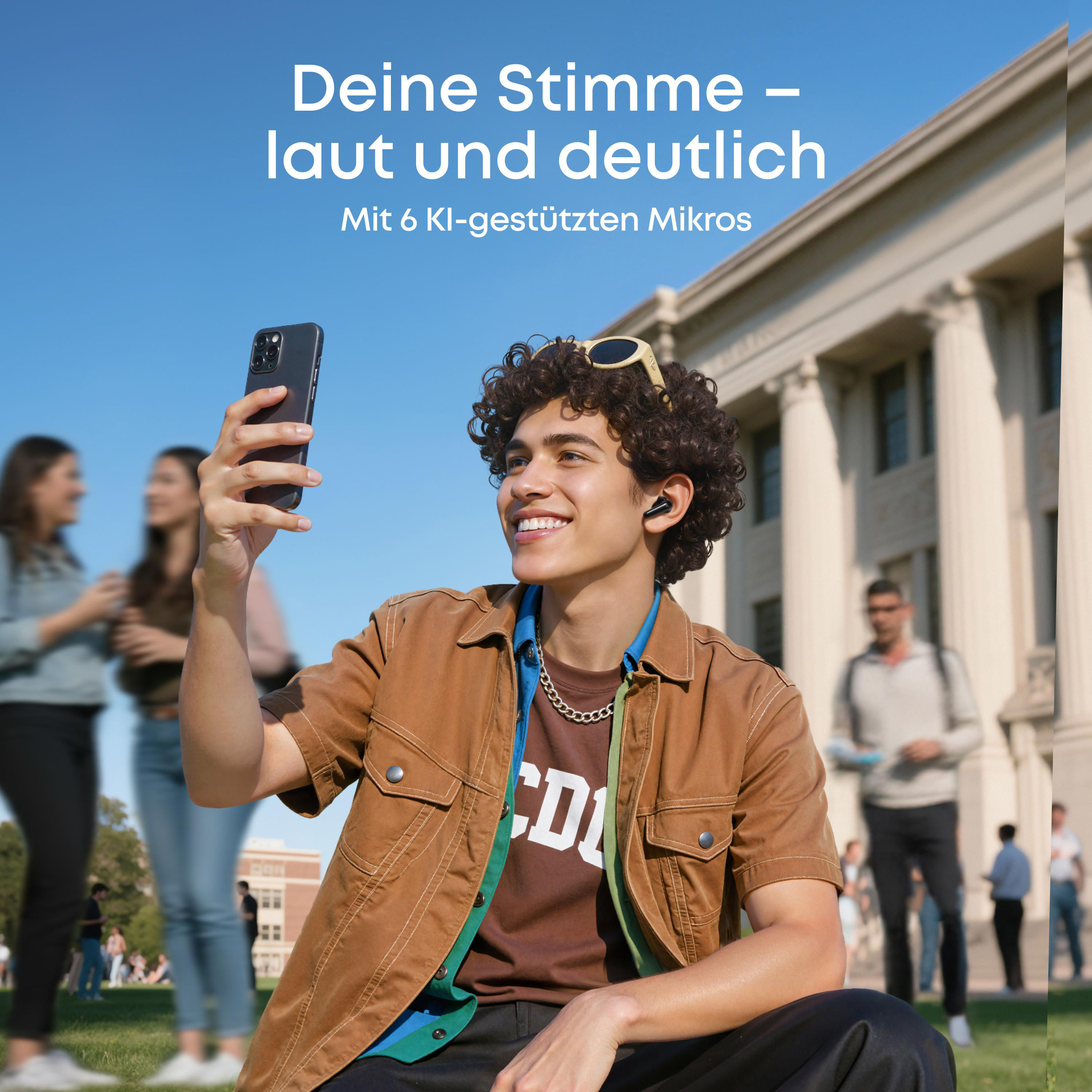 Ein junger Mann macht ein Selfie mit seinem Smartphone, draußen vor einem Gebäude.