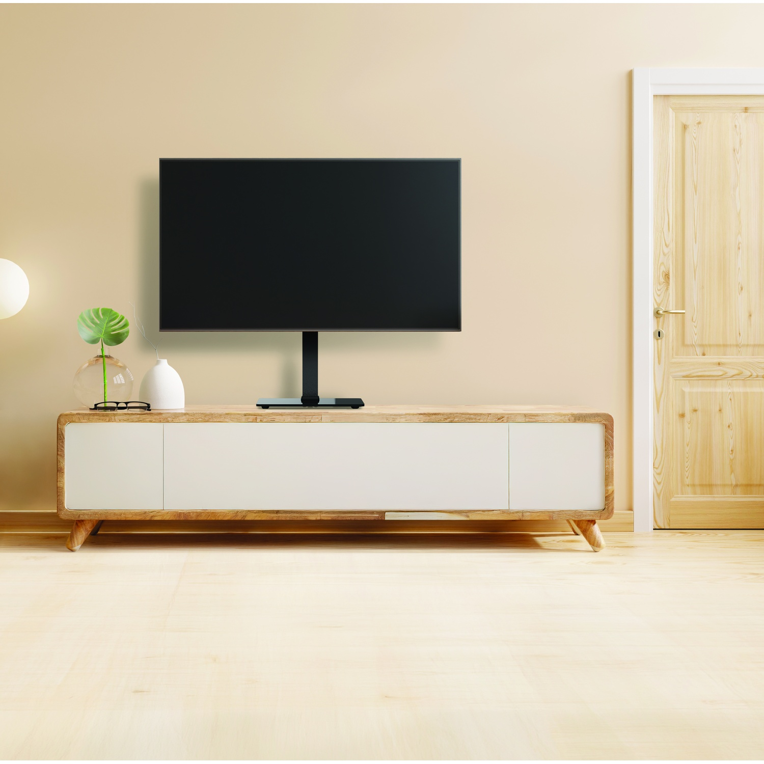Un televisore moderno è posato su un mobile in legno con ante bianche.