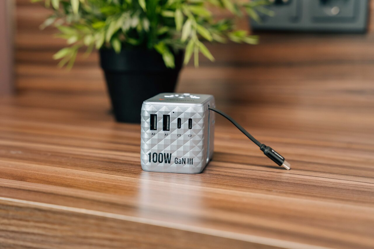 Ezüst 100W GaN III töltőadapter USB-A és USB-C portokkal faasztalon.