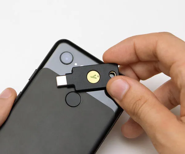 Ein YubiKey-Sicherheitsschlüssel wird an einen USB-C-Anschluss eines schwarzen Smartphones angeschlossen.