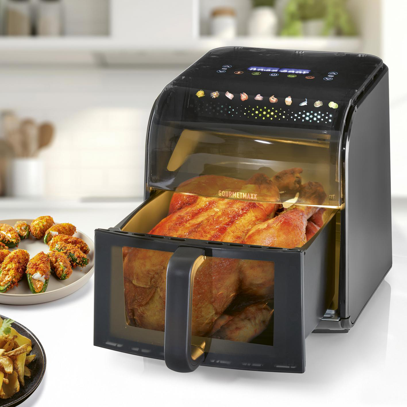 Ein Brathähnchen und Jalapeño-Popper in einem schwarzen Airfryer auf einer Küchentheke.
