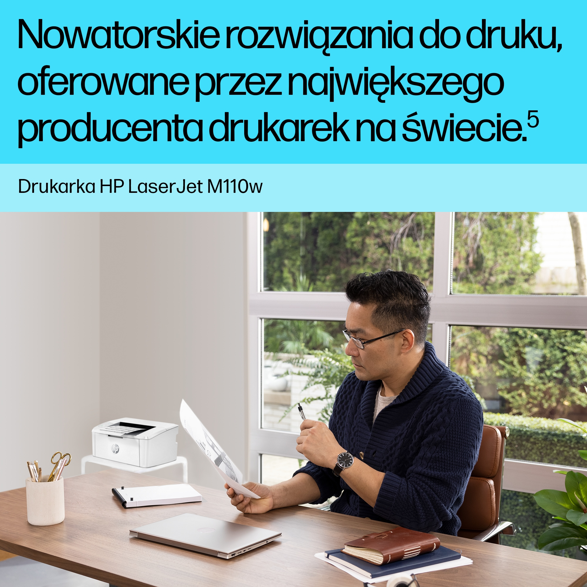 Mężczyzna siedzi przy biurku, przegląda dokumenty, obok drukarka.