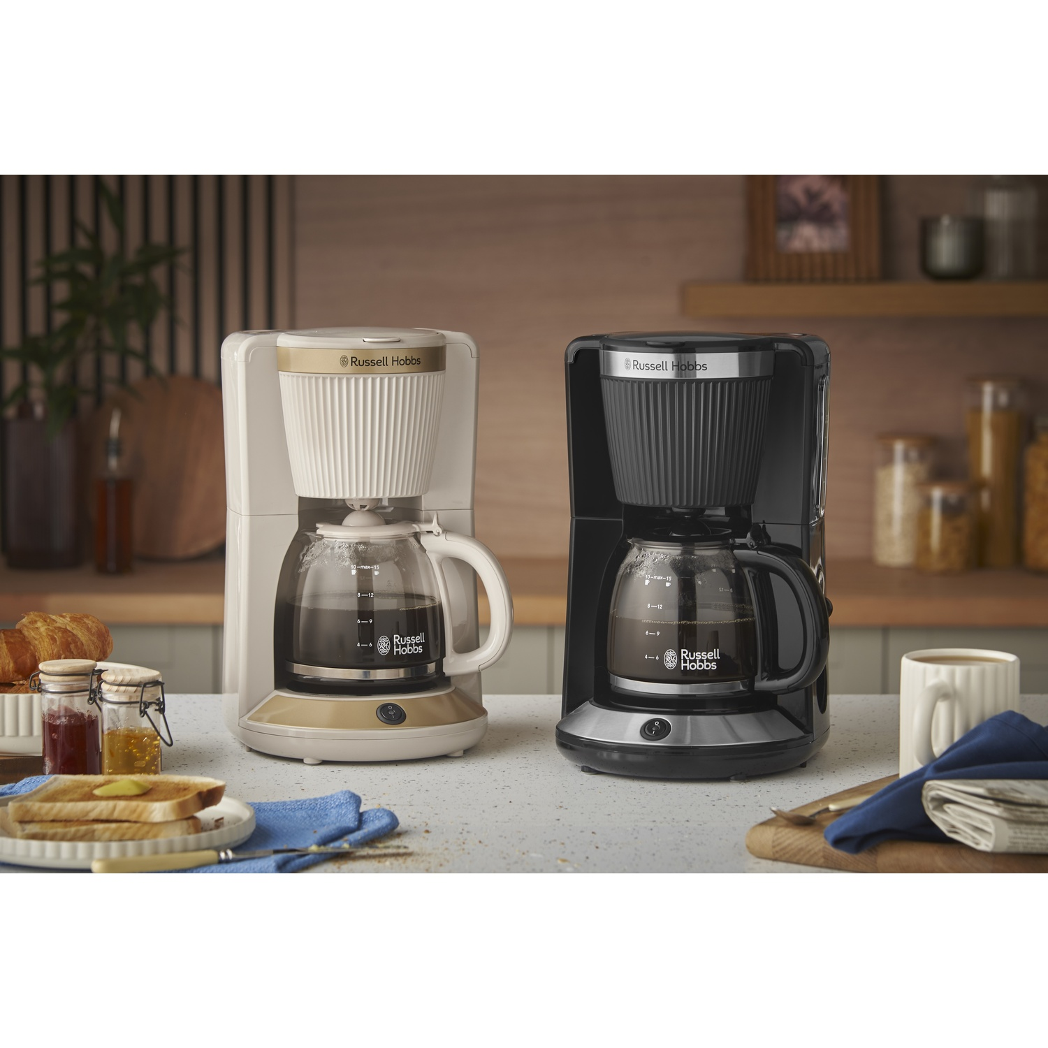 Twee Russell Hobbs koffiezetapparaten, een witte en een zwarte, staan naast elkaar.