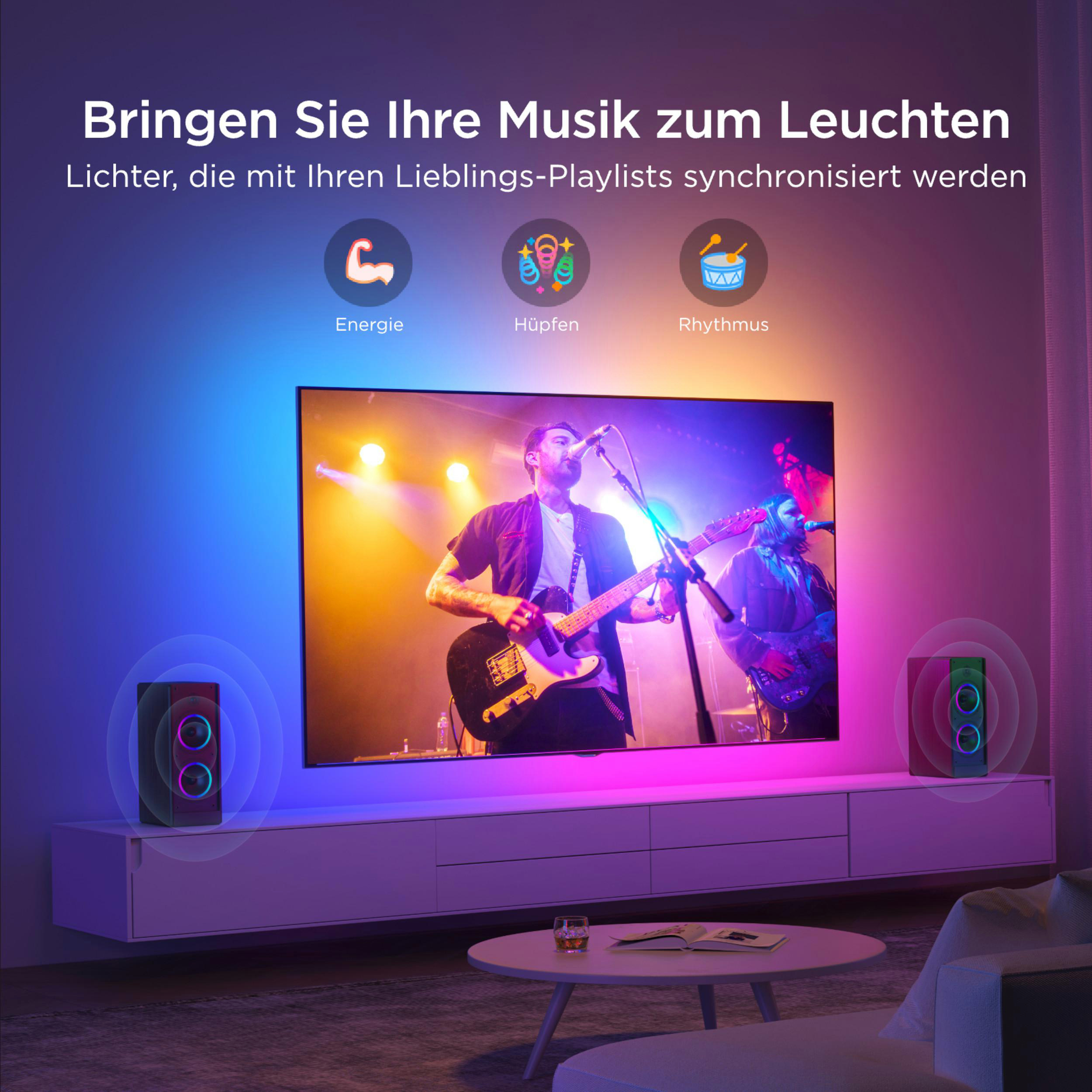 Eine Band spielt auf einer Bühne, beleuchtet von bunten Lichtern. Daneben stehen Lautsprecher.