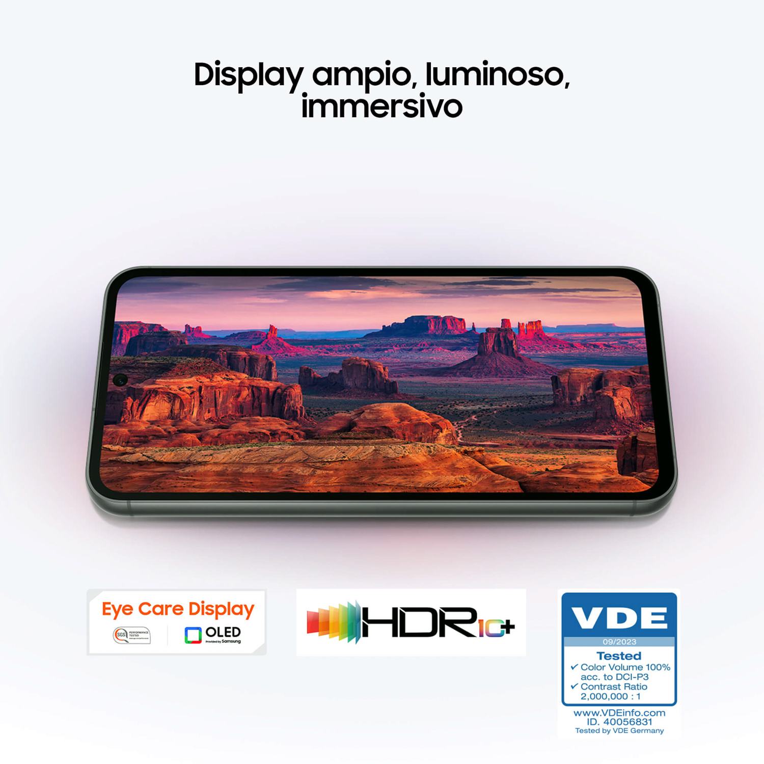 Uno smartphone mostra un paesaggio desertico con formazioni rocciose rosse e cielo blu.