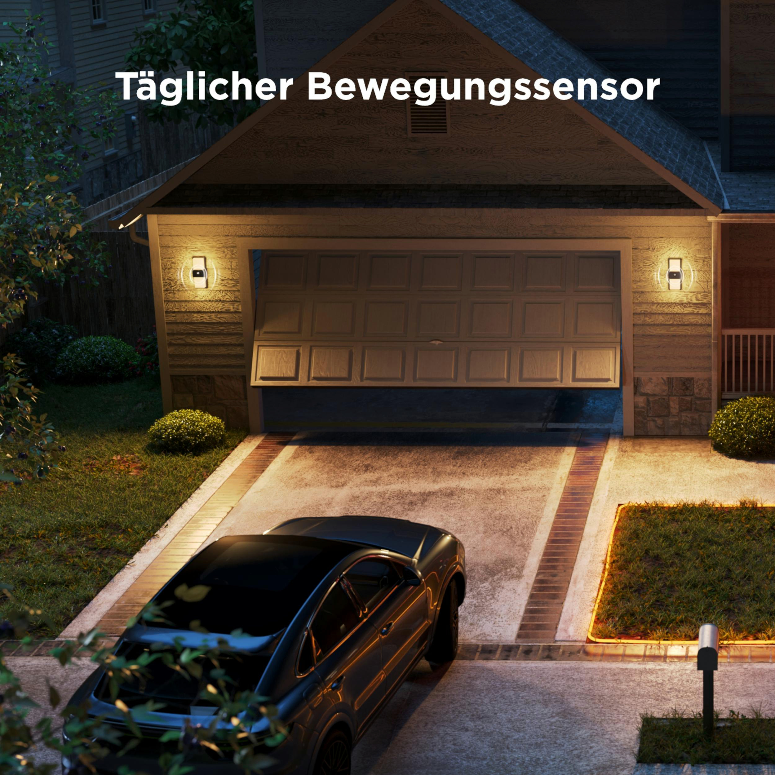 Ein schwarzes Auto parkt vor einem Haus mit Garagentor. Lichter leuchten.