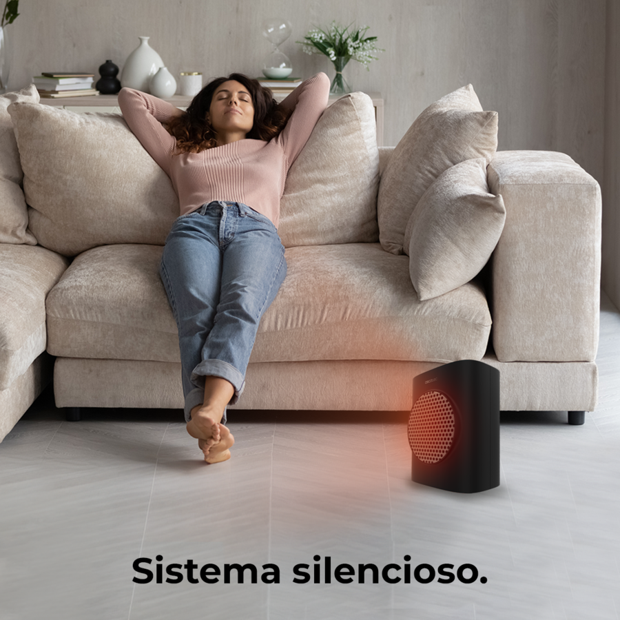 Una mujer se relaja en un sofá, con un calefactor cerca.
