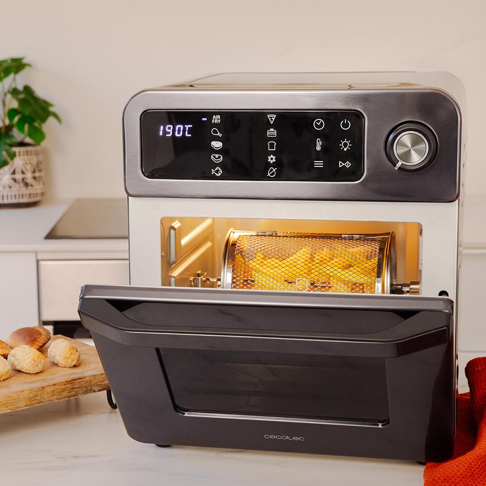 Un horno freidora de aire plateado con la puerta abierta, cocinando papas fritas.