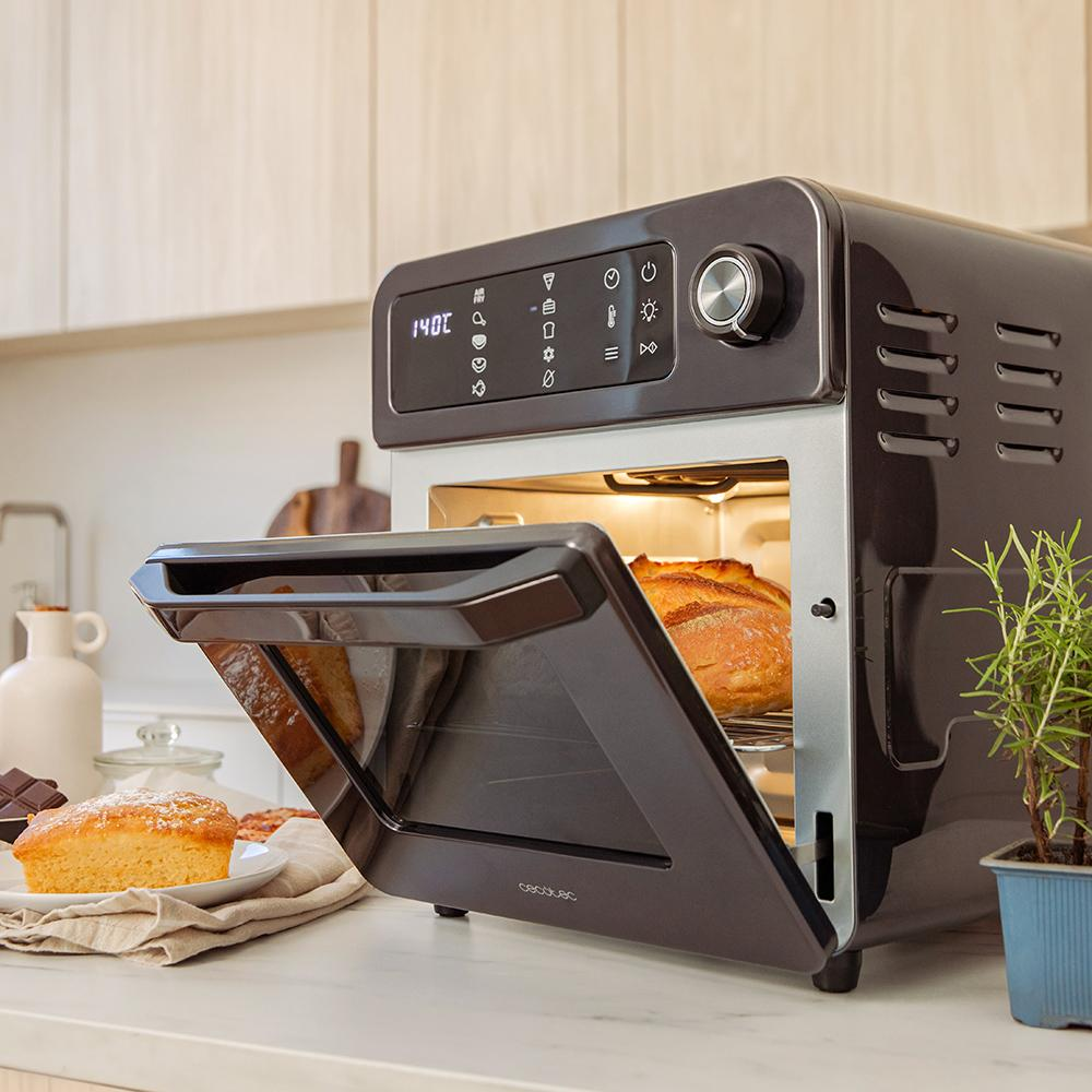 Un horno oscuro con la puerta abierta, contiene pan. A su lado, un trozo de pastel.