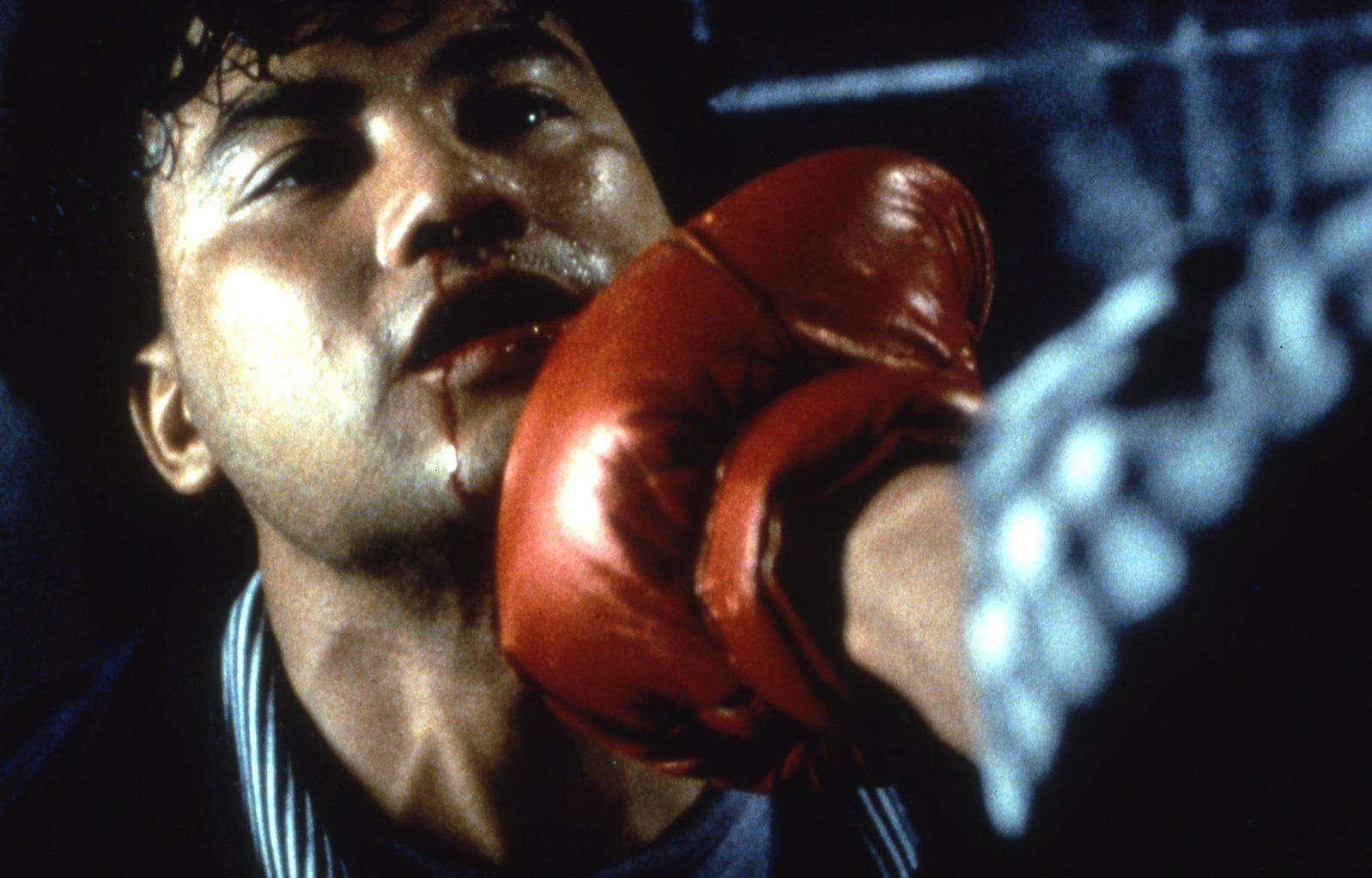 Ein Boxer erhält einen roten Handschuhschlag ins Gesicht, Blut tropft.