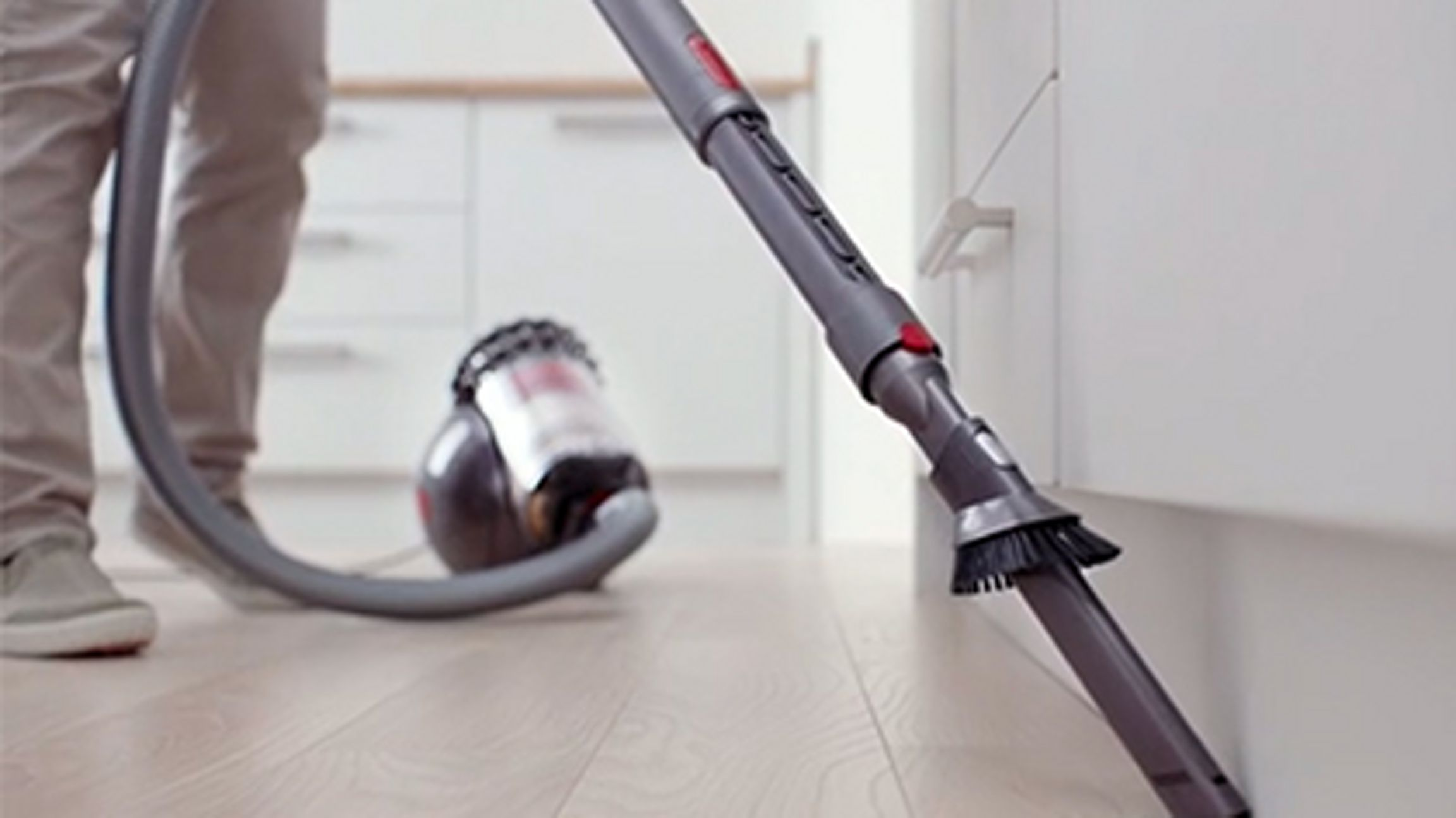 Une personne passe l'aspirateur Dyson sur le sol.