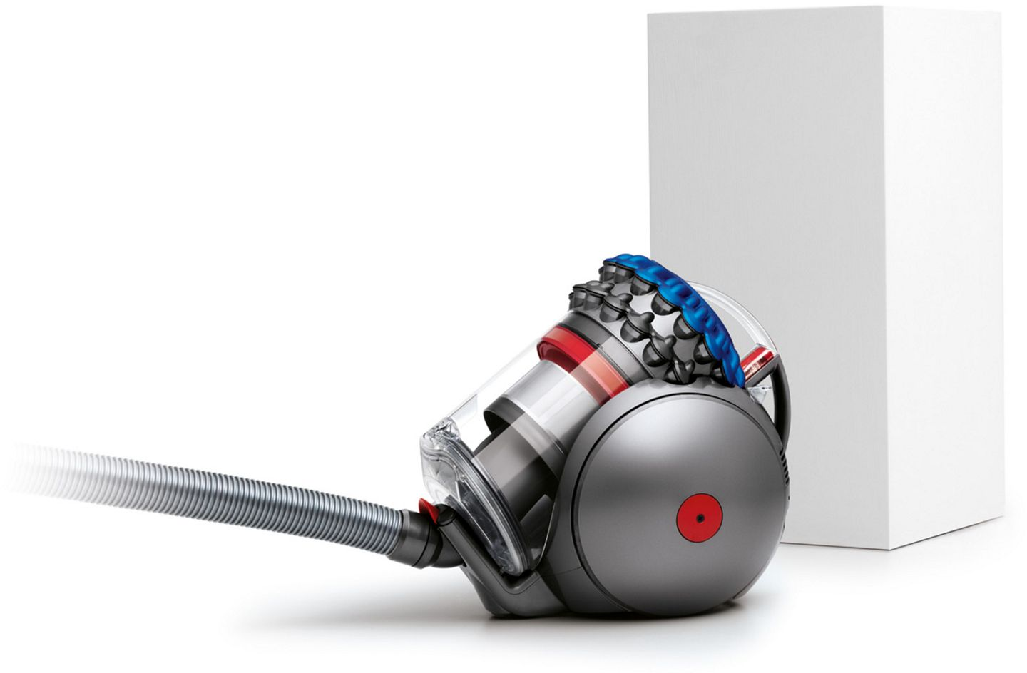 Aspirateur gris avec détail bleu et rouge, à côté d'une boîte blanche.