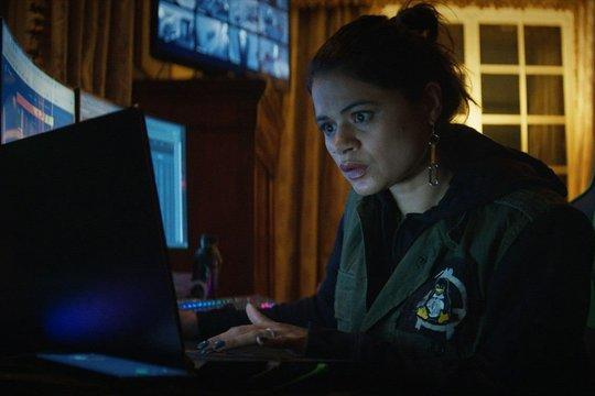 Eine Frau mit dunklem Haar blickt konzentriert auf einen Laptop-Bildschirm.