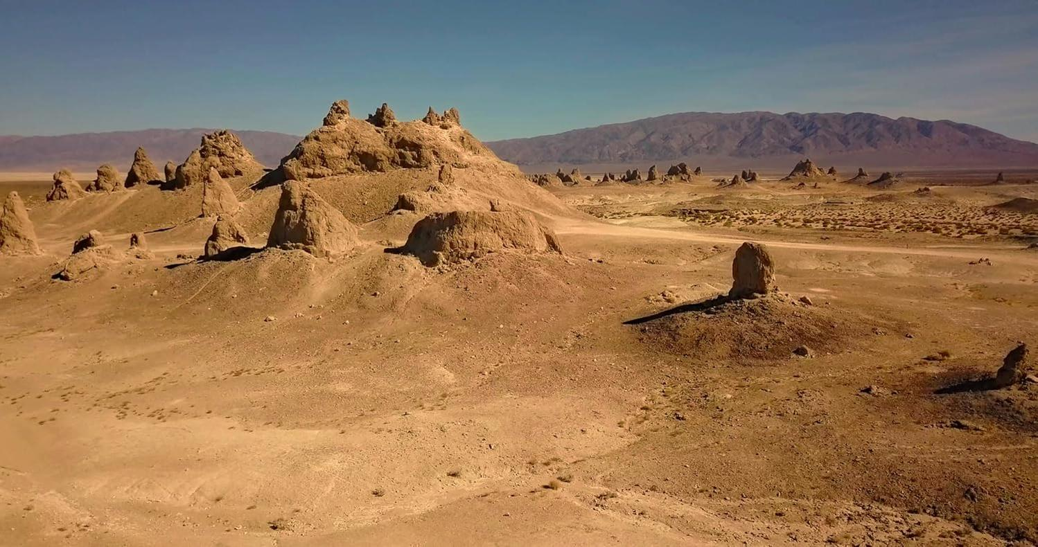 Braune Felsformationen in einer trockenen Wüstenlandschaft unter blauem Himmel.