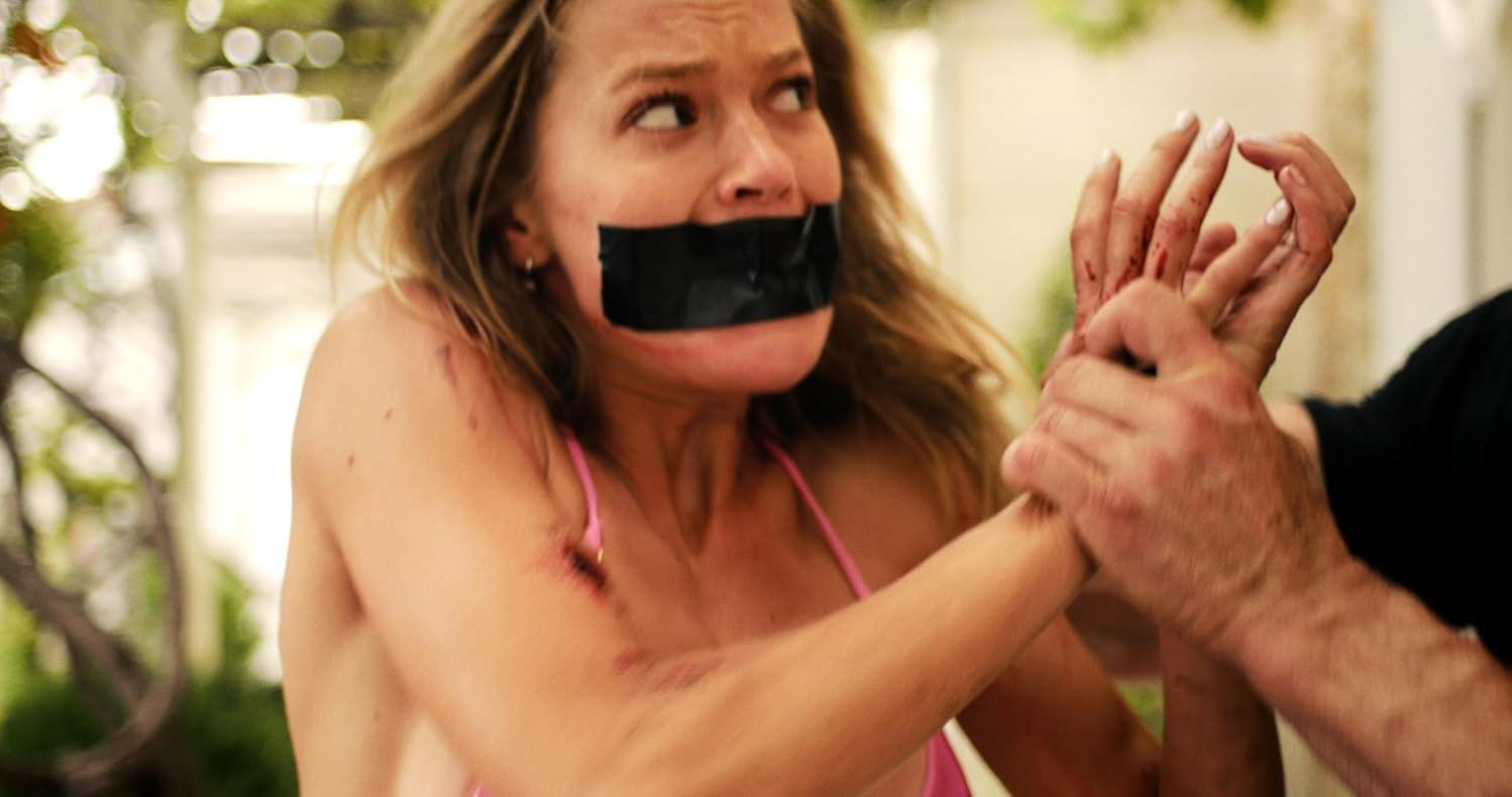 Eine Frau mit Klebeband über dem Mund wird festgehalten. Ihre Arme sind zerkratzt.