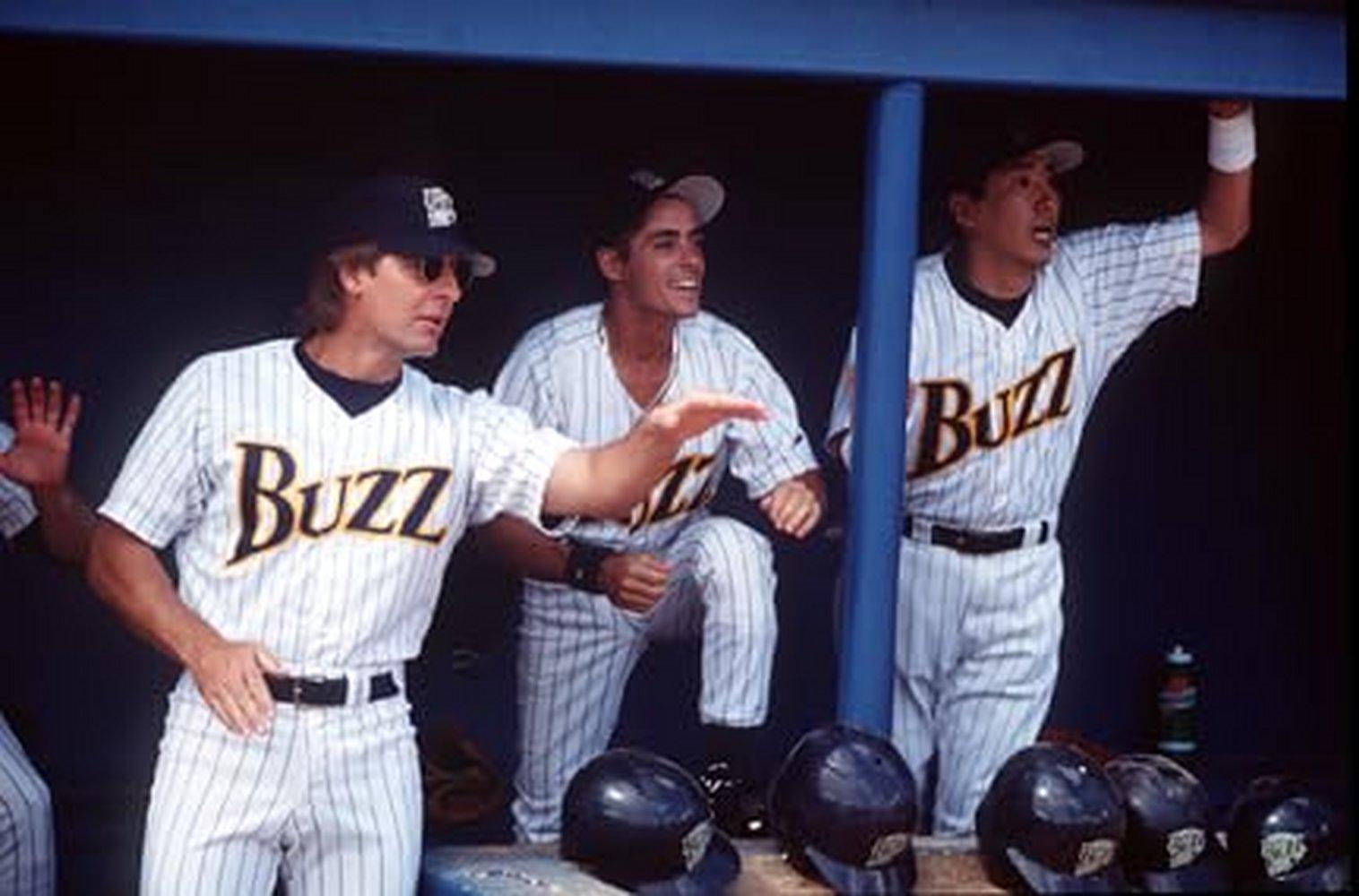 Drei Baseballspieler in gestreiften Trikots mit „Buzz“ stehen im Schatten.