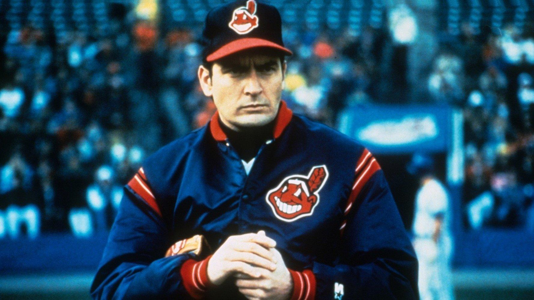 Ein Mann in Baseballkleidung mit einer Cap und Jacke steht im Vordergrund.
