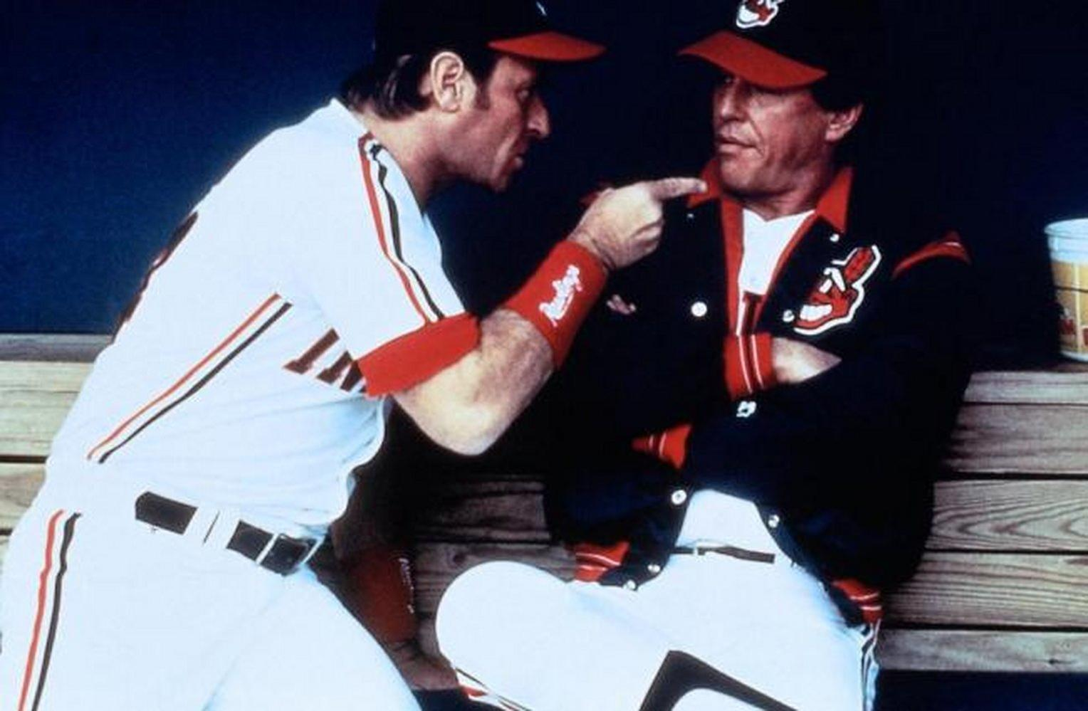 Zwei Baseballspieler in Uniform sitzen und unterhalten sich. Einer zeigt auf den anderen.